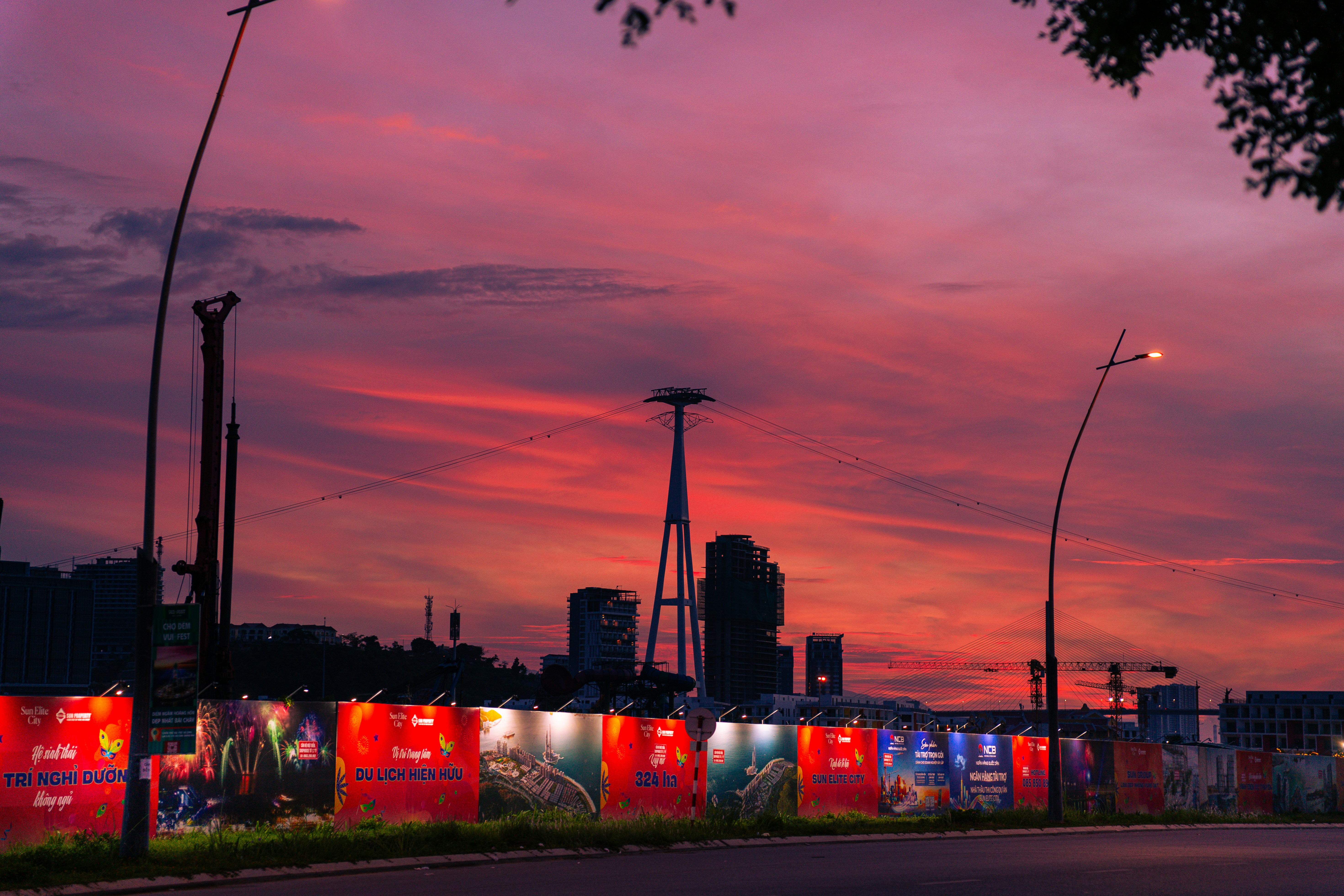 Langit matahari terbenam merah muda yang cerah di atas bangunan kota dan pagar yang diterangi.