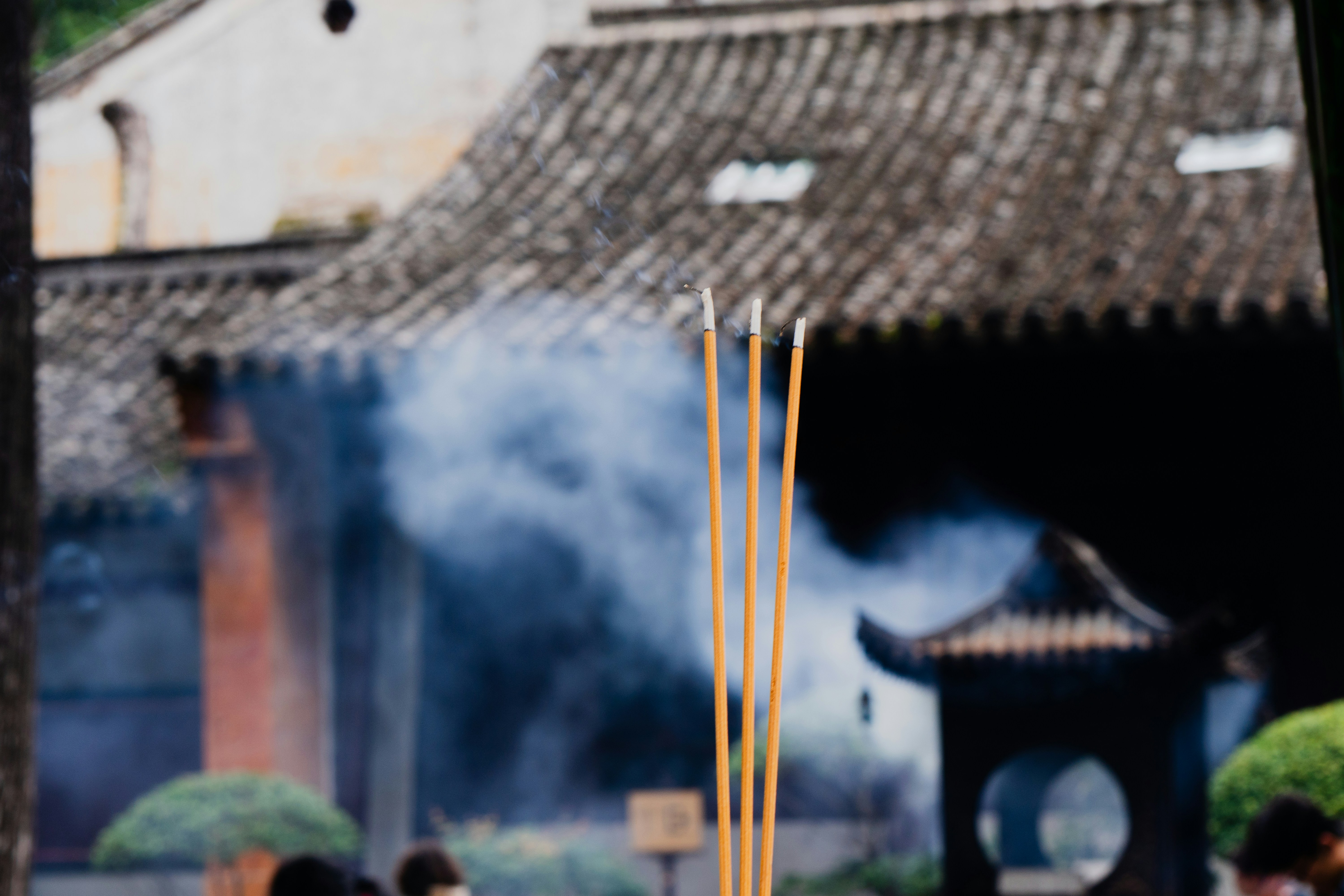 A group of visitors lighting incense sticks at the base of the pagoda, with smoke rising towards the sky