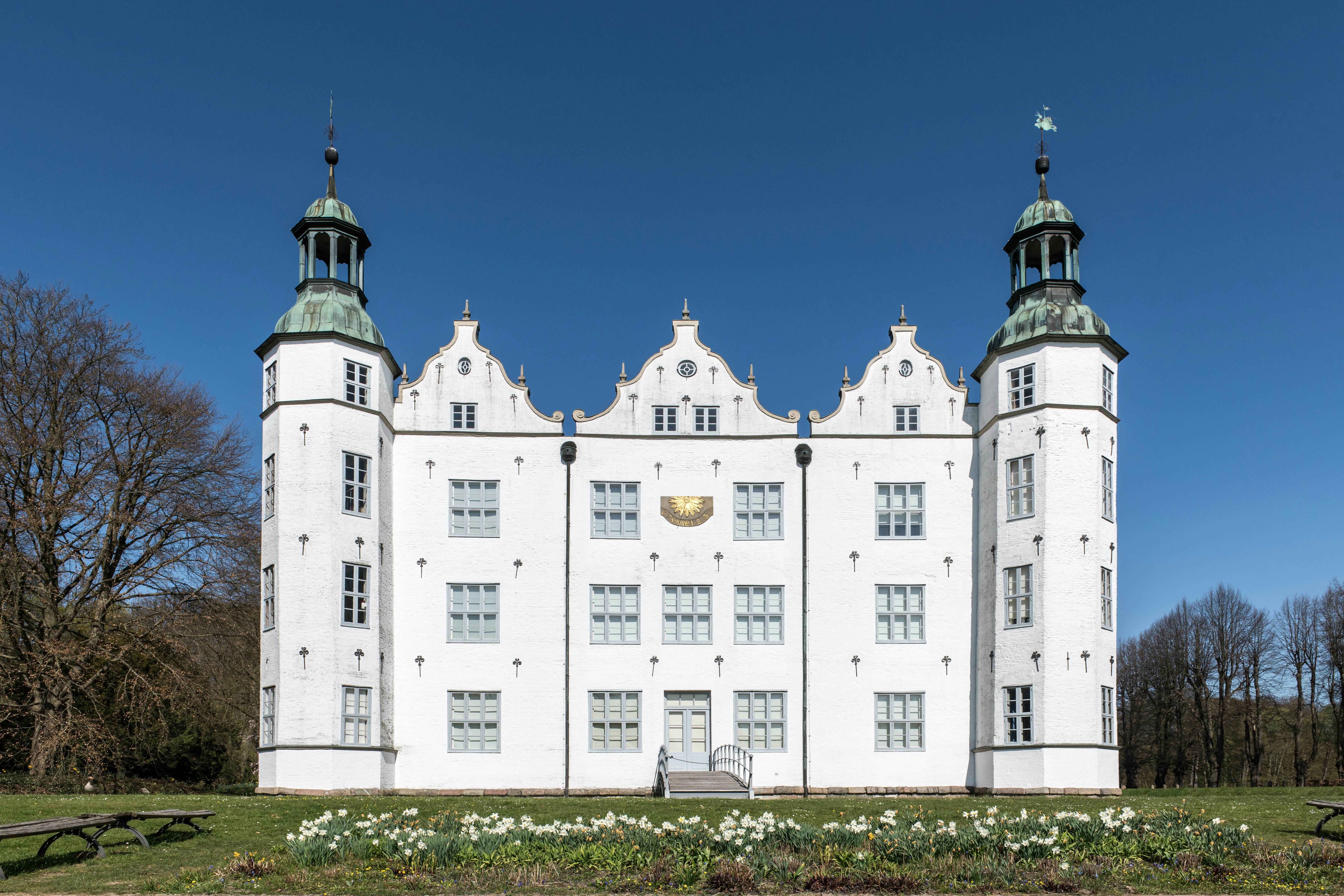 Historic white castle with green turrets against a blue sky.