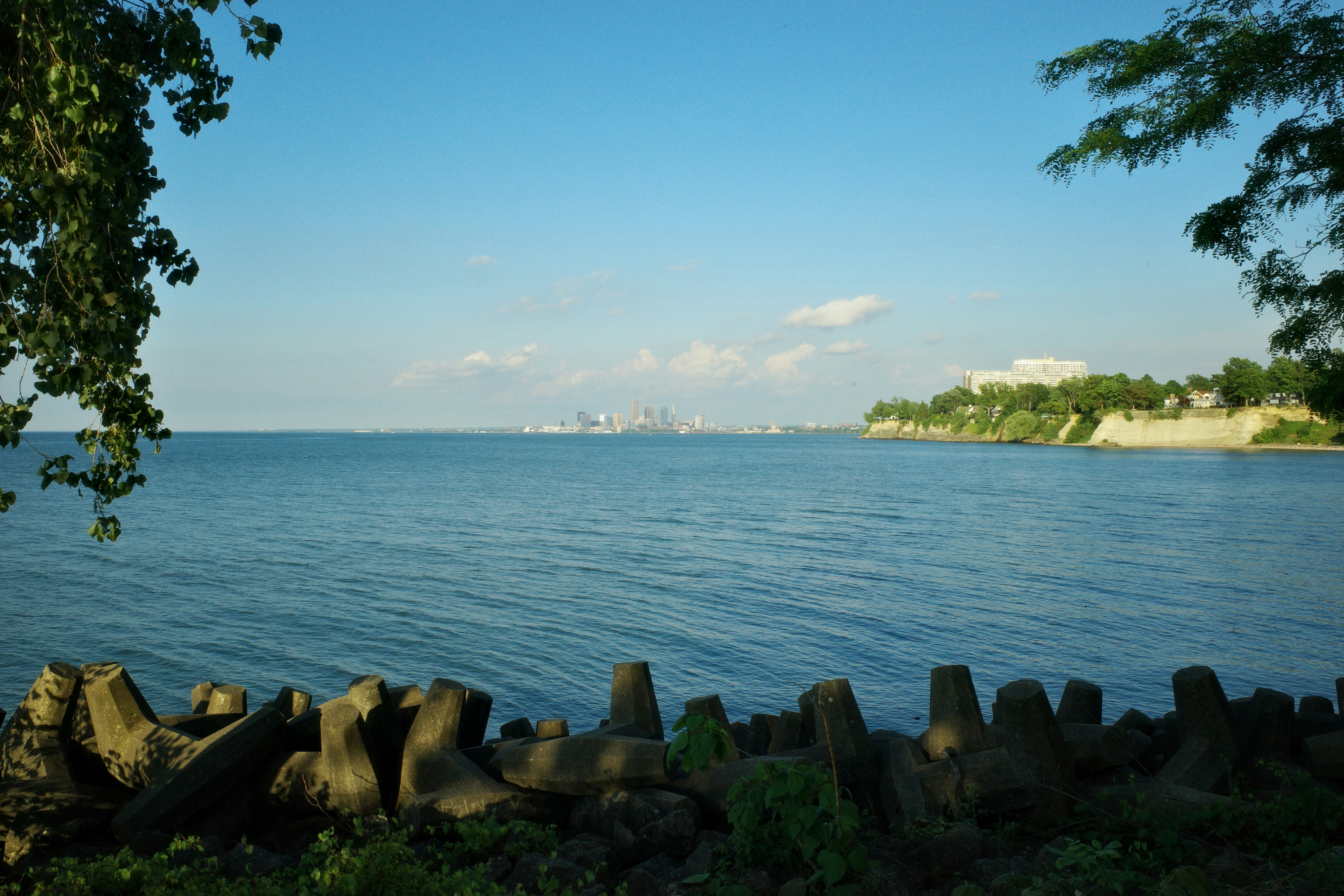 Scenic lake view with concrete barriers and distant city skyline.