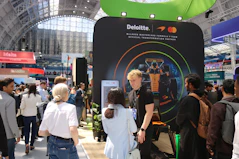 Attendees interact with a deloitte and mastercard exhibition booth.