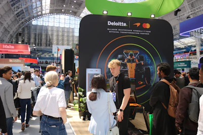 Attendees interact with a deloitte and mastercard exhibition booth.