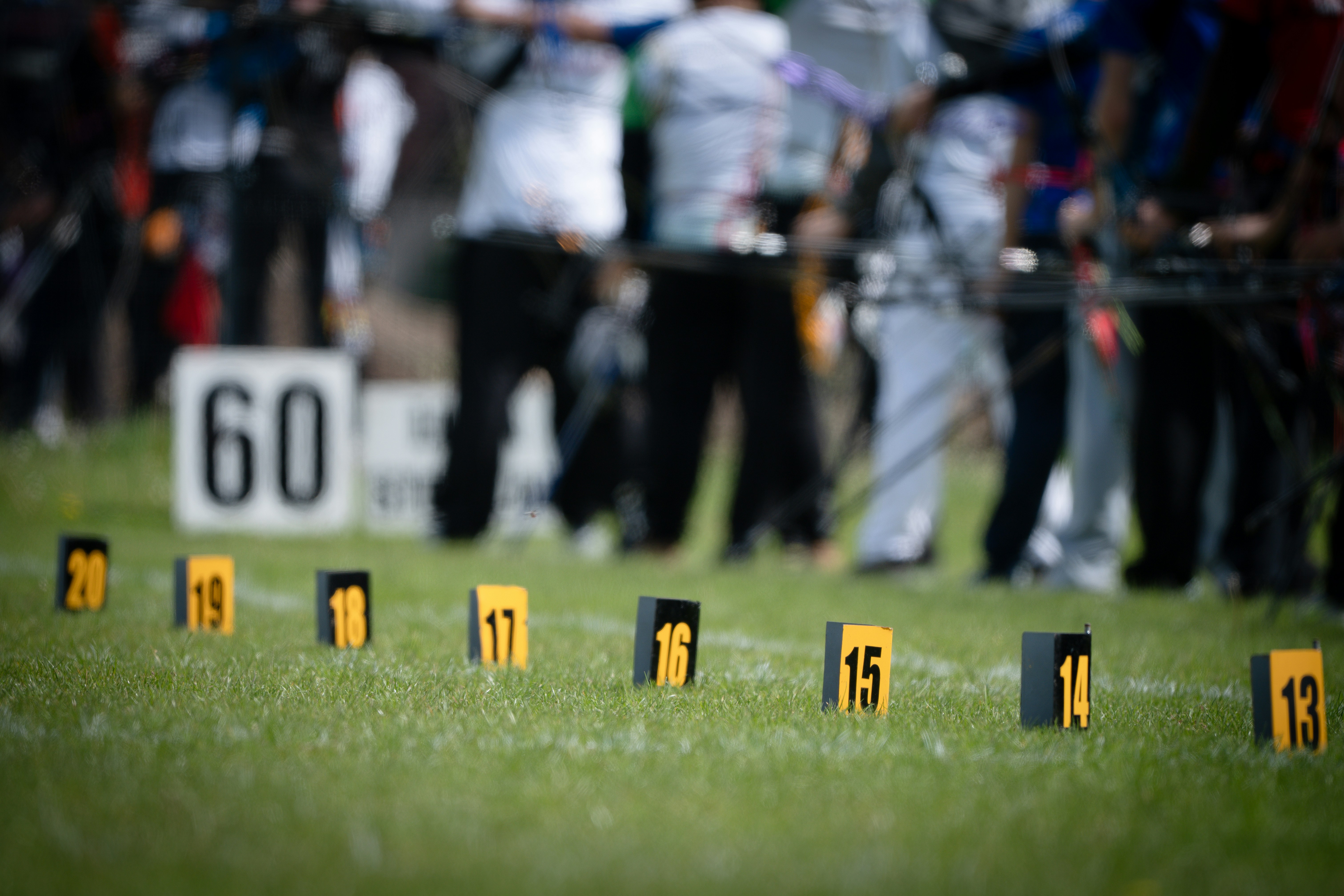 Numbered markers on green grass with people in the background
