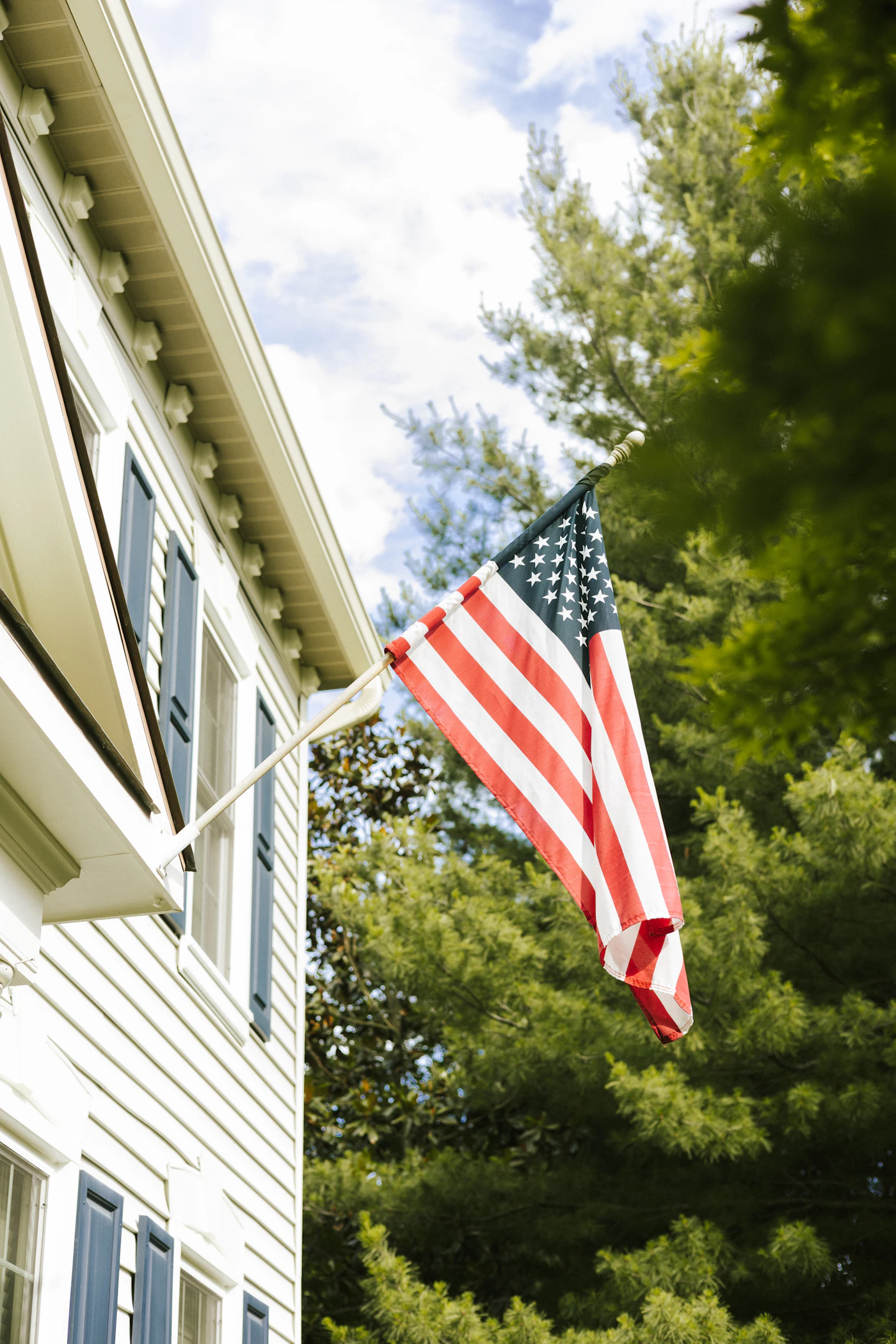 An American flag flying outside a white two-story home