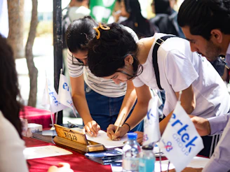 People signing up at an outdoor event desk.