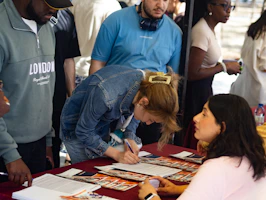 Woman signing paperwork at an outdoor event registration.