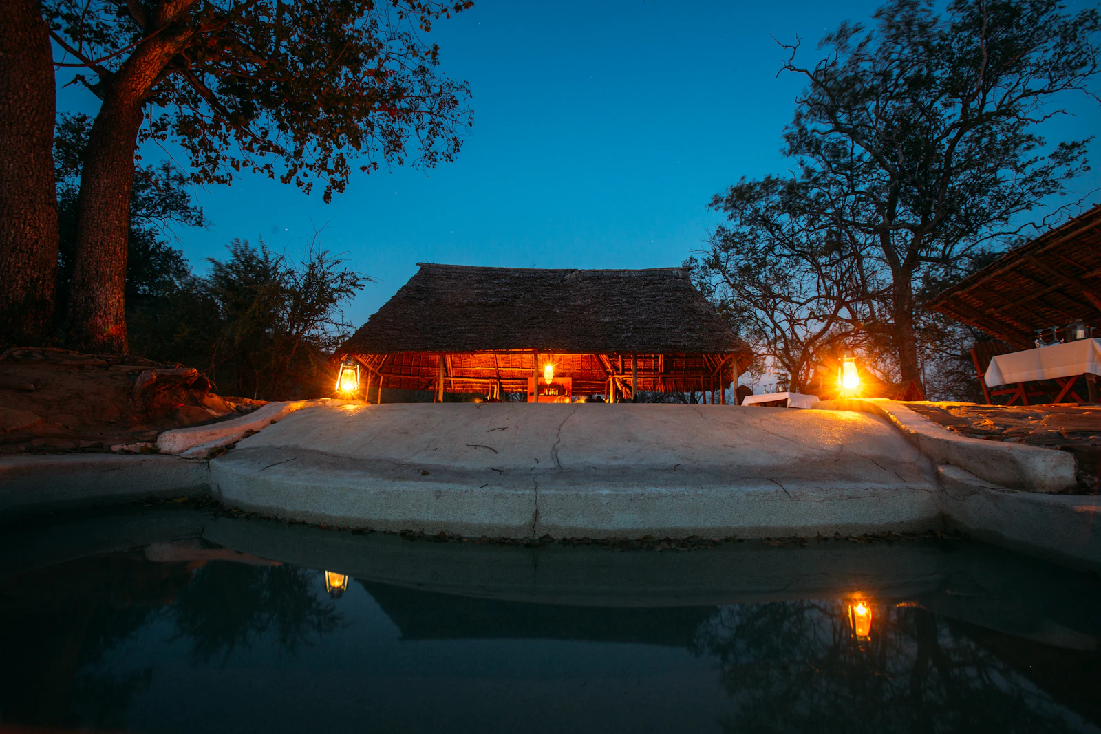 Illuminated safari lodge with a swimming pool at dusk
