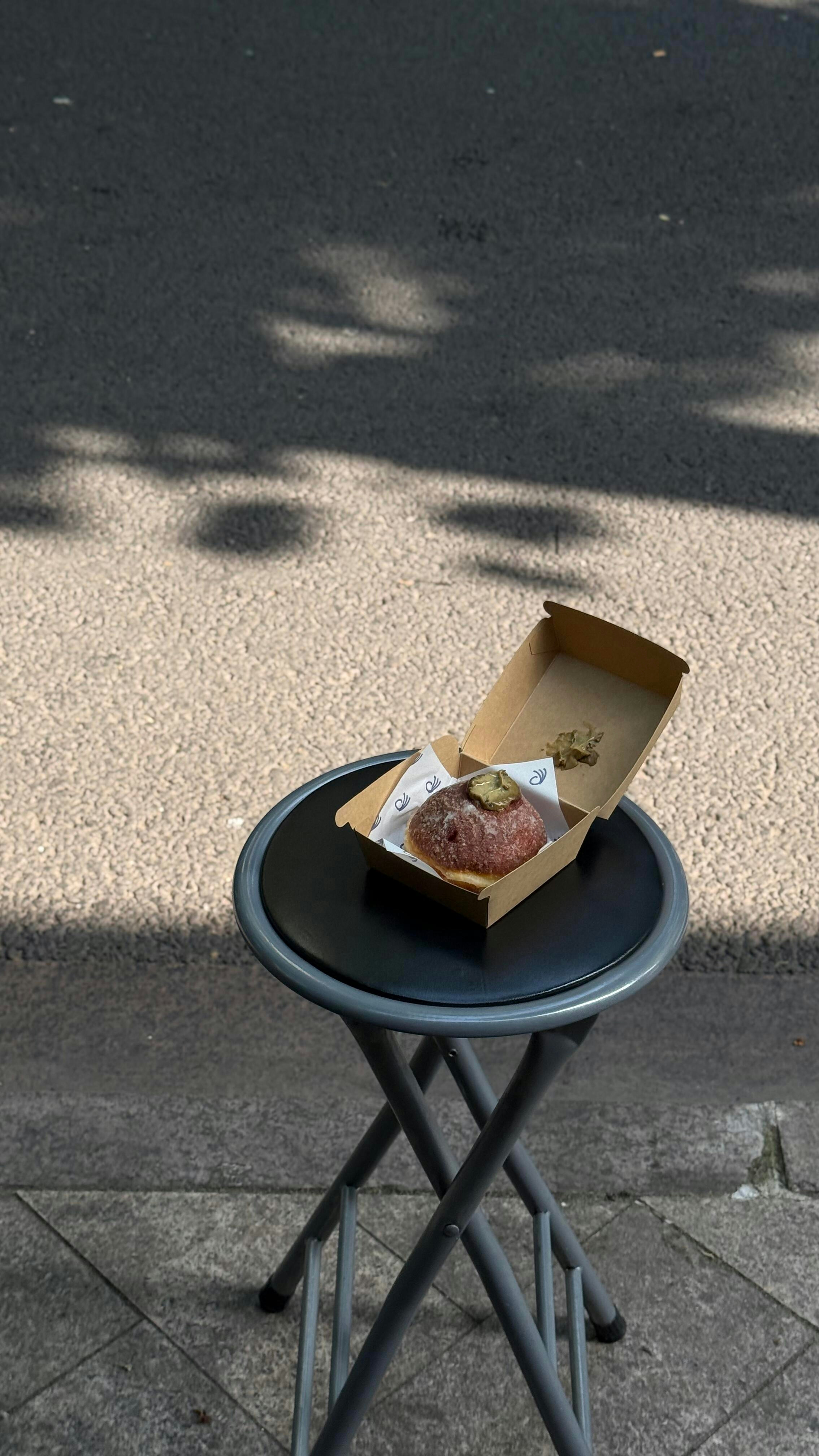 Une pâtisserie dans une boîte sur un tabouret pliant dehors.