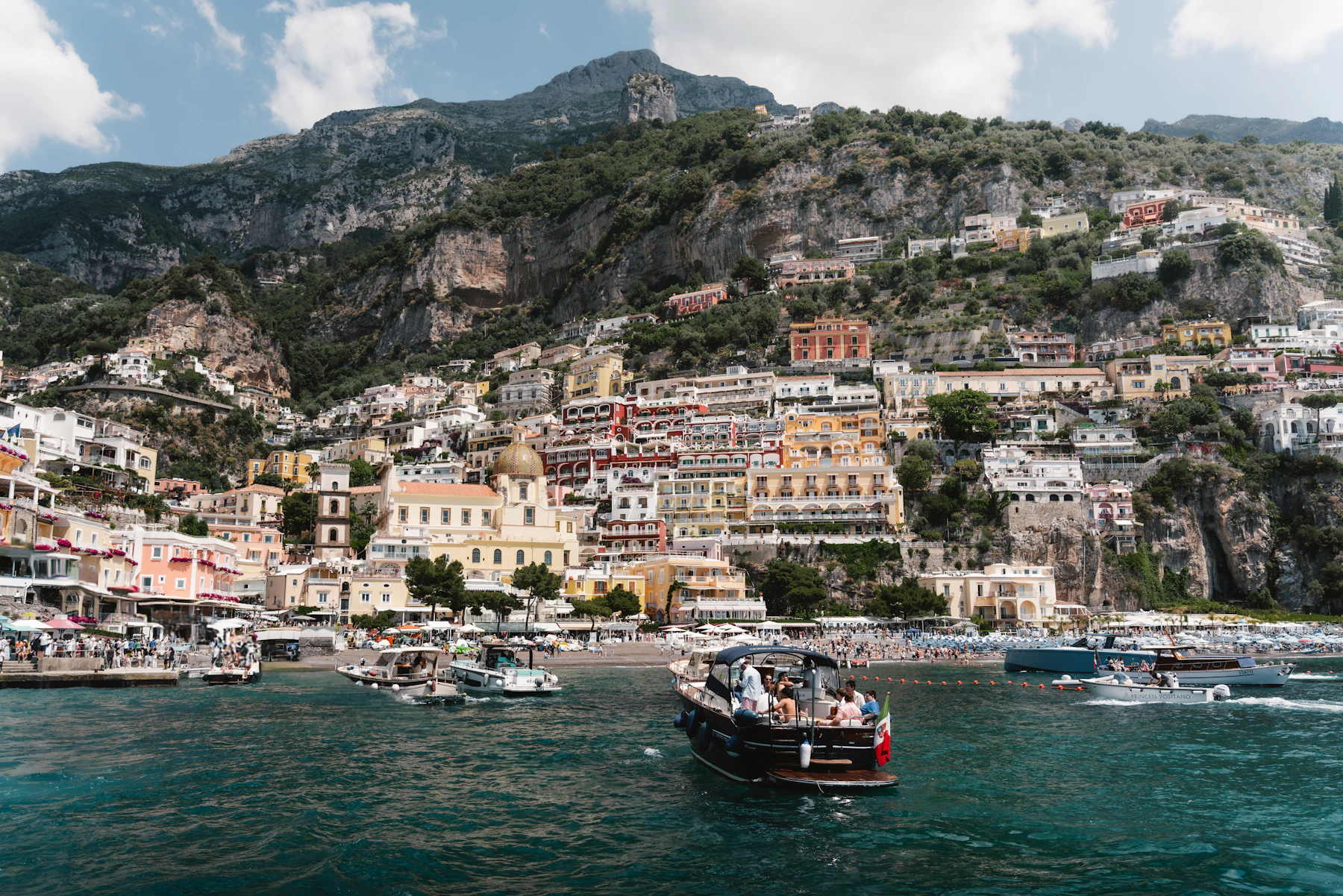 Boats drifting below the colorful cliffside houses of Positano, Italy