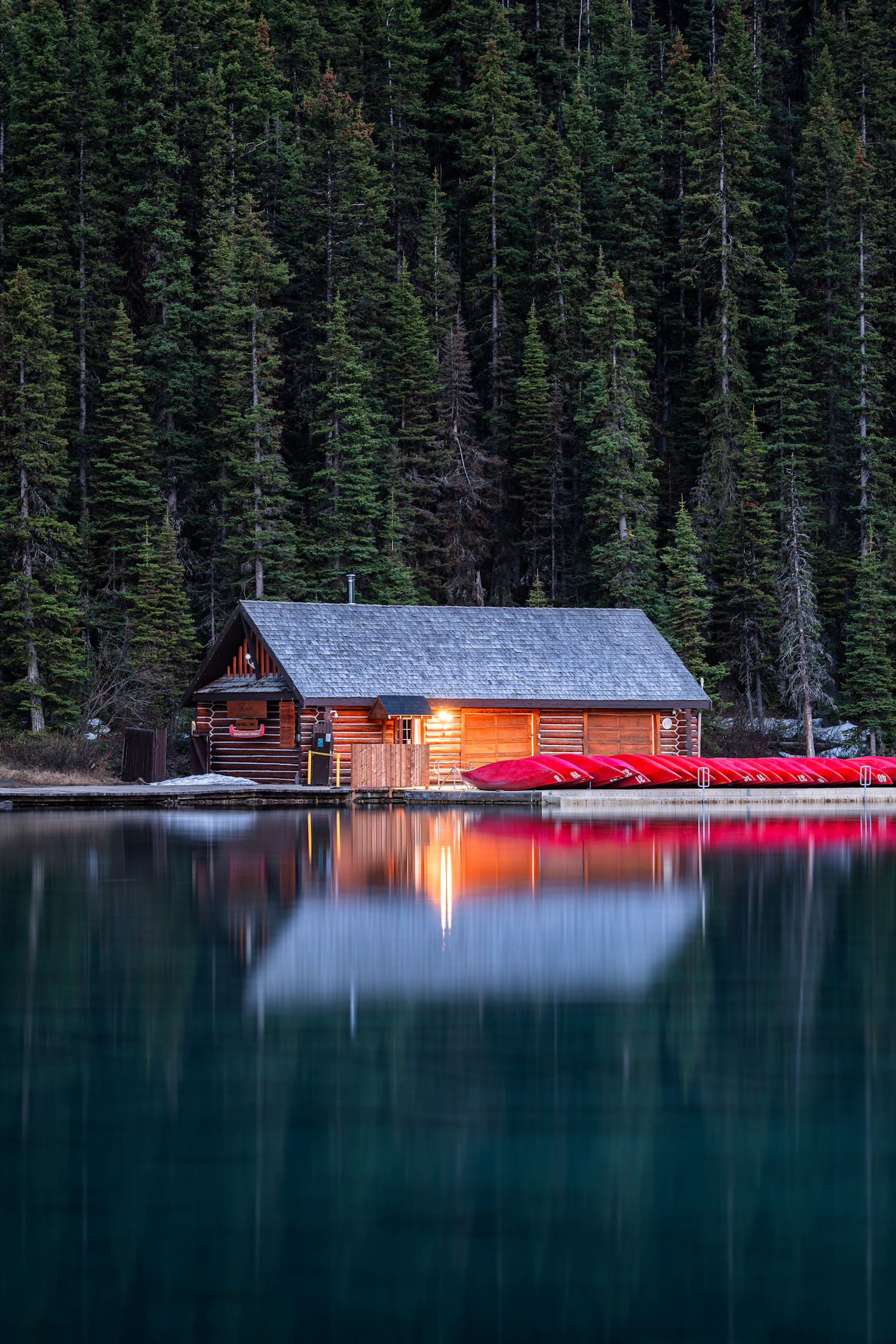 Chalet de bois et canots rouges au bord d’un lac
