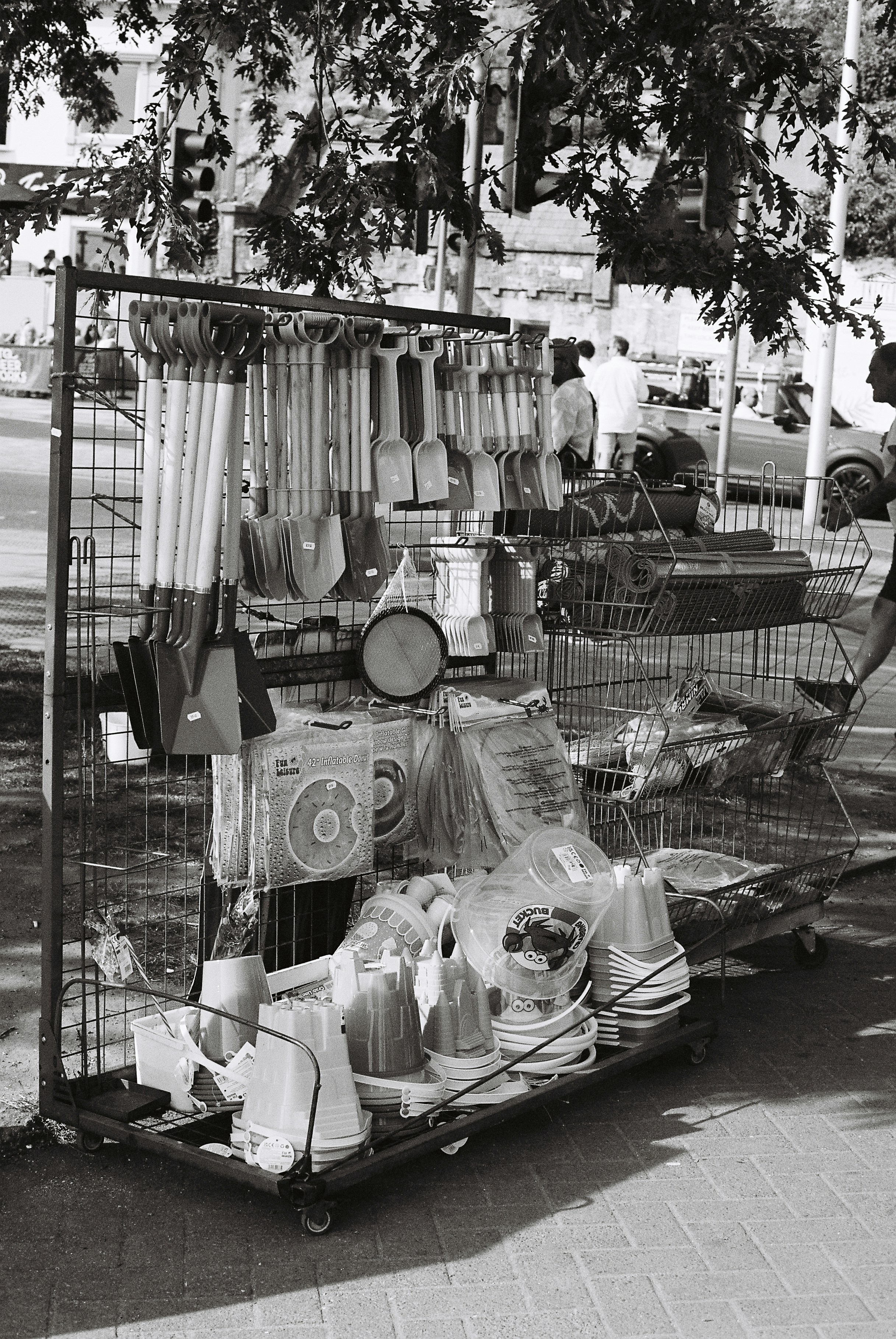 Herramientas de jardinería y artículos domésticos expuestos en un carrito de calle.