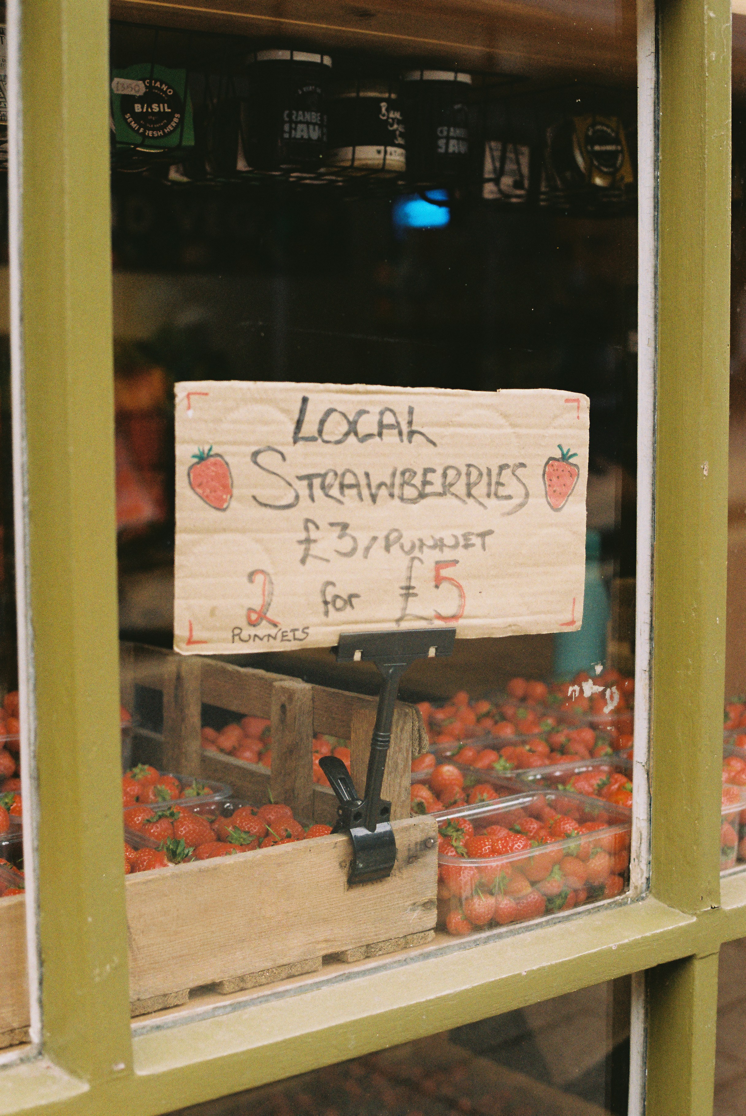 Cartel local de fresas y exposición de fruta fresca en una tienda.