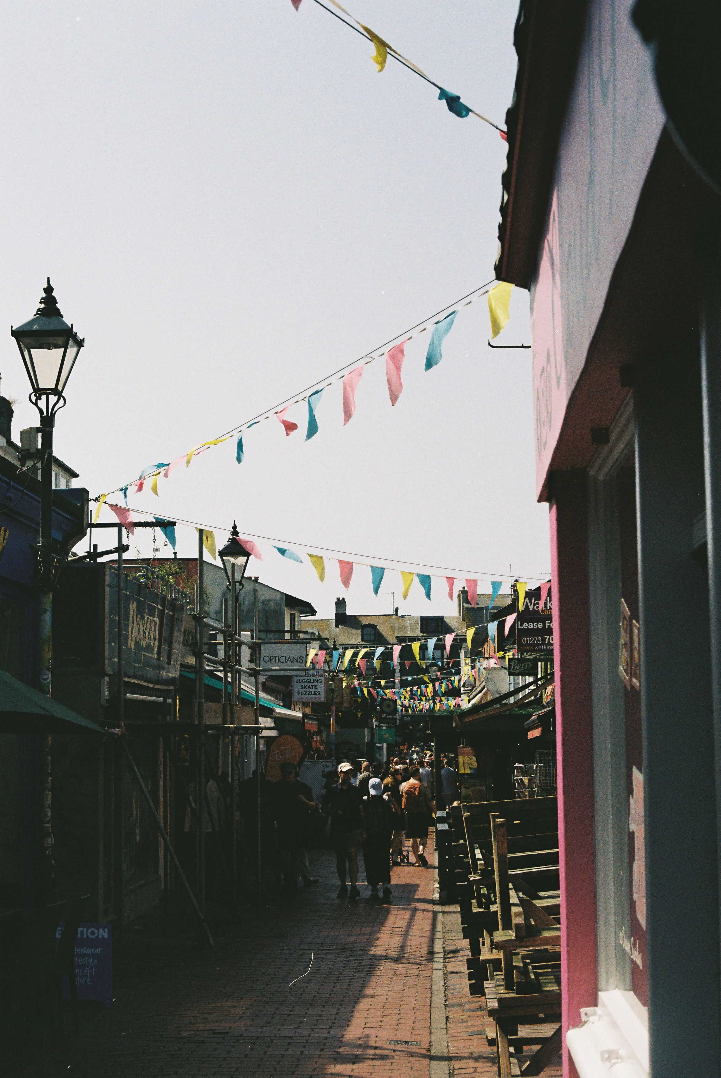 Una calle estrecha adornada con banderinas coloridas y gente caminando.