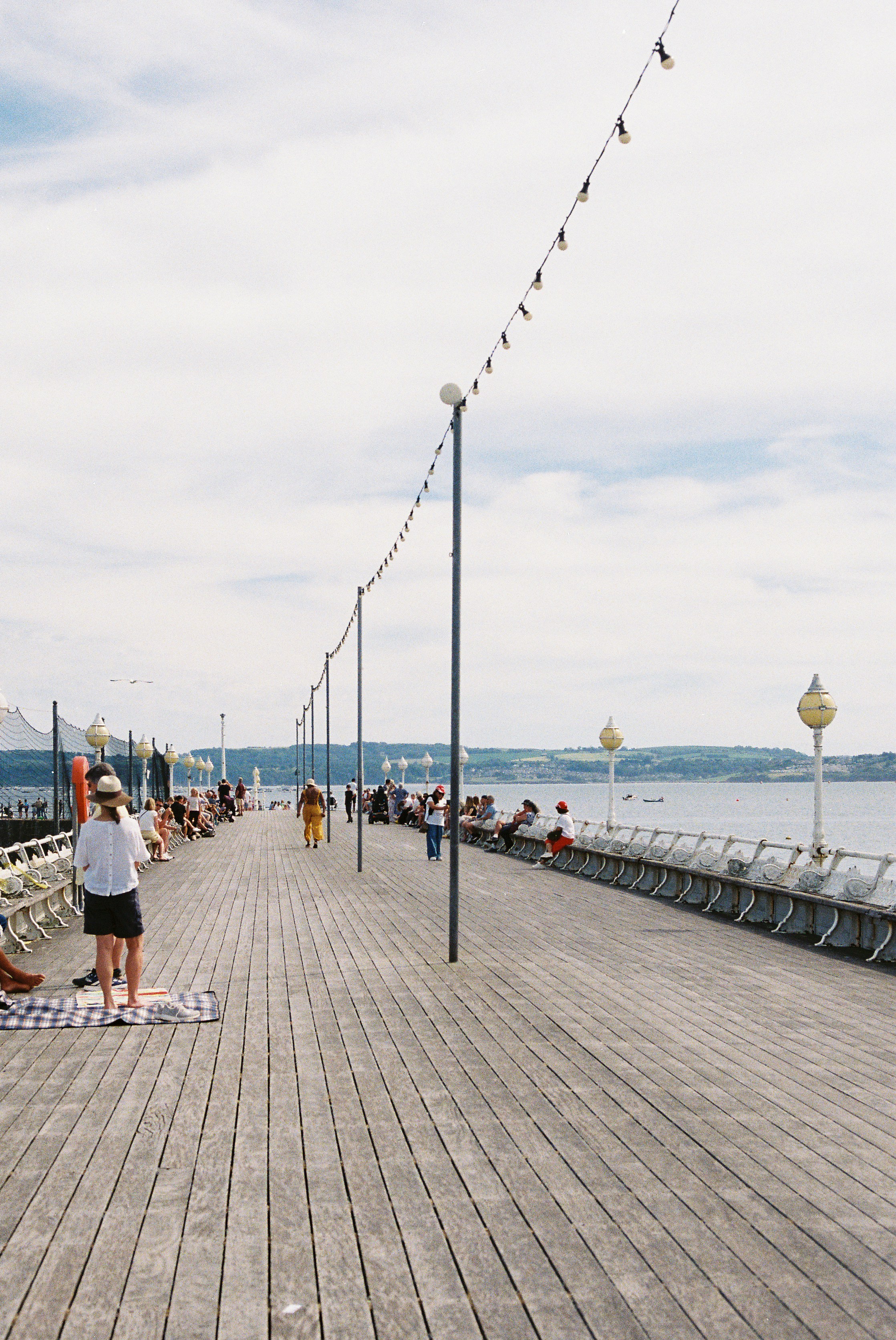 La gente disfruta de un día soleado en un largo muelle de madera.