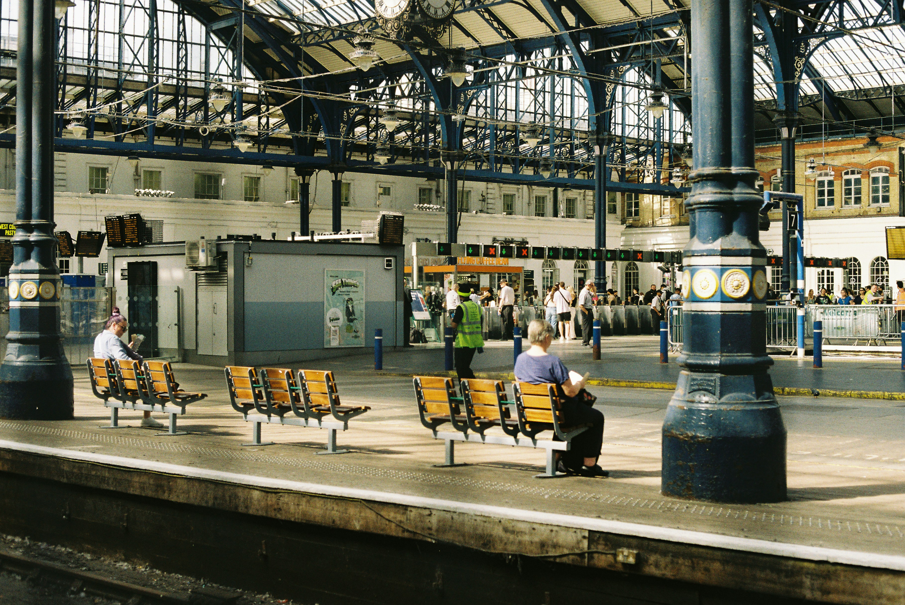 Gente esperando en bancos en el andén de una estación de tren.