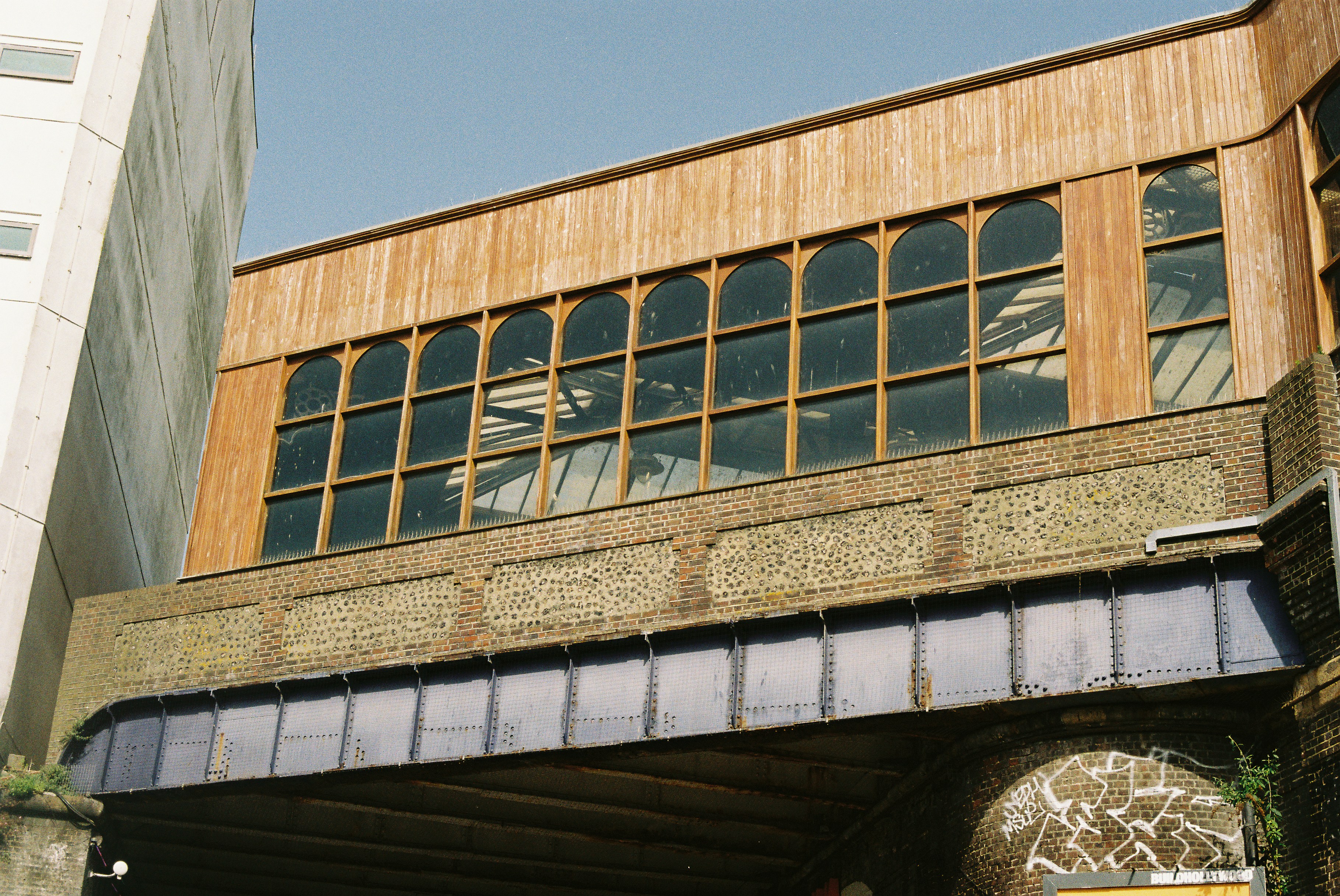 Fachada del edificio con ventanas arqueadas, revestimiento de madera y detalles de ladrillo.