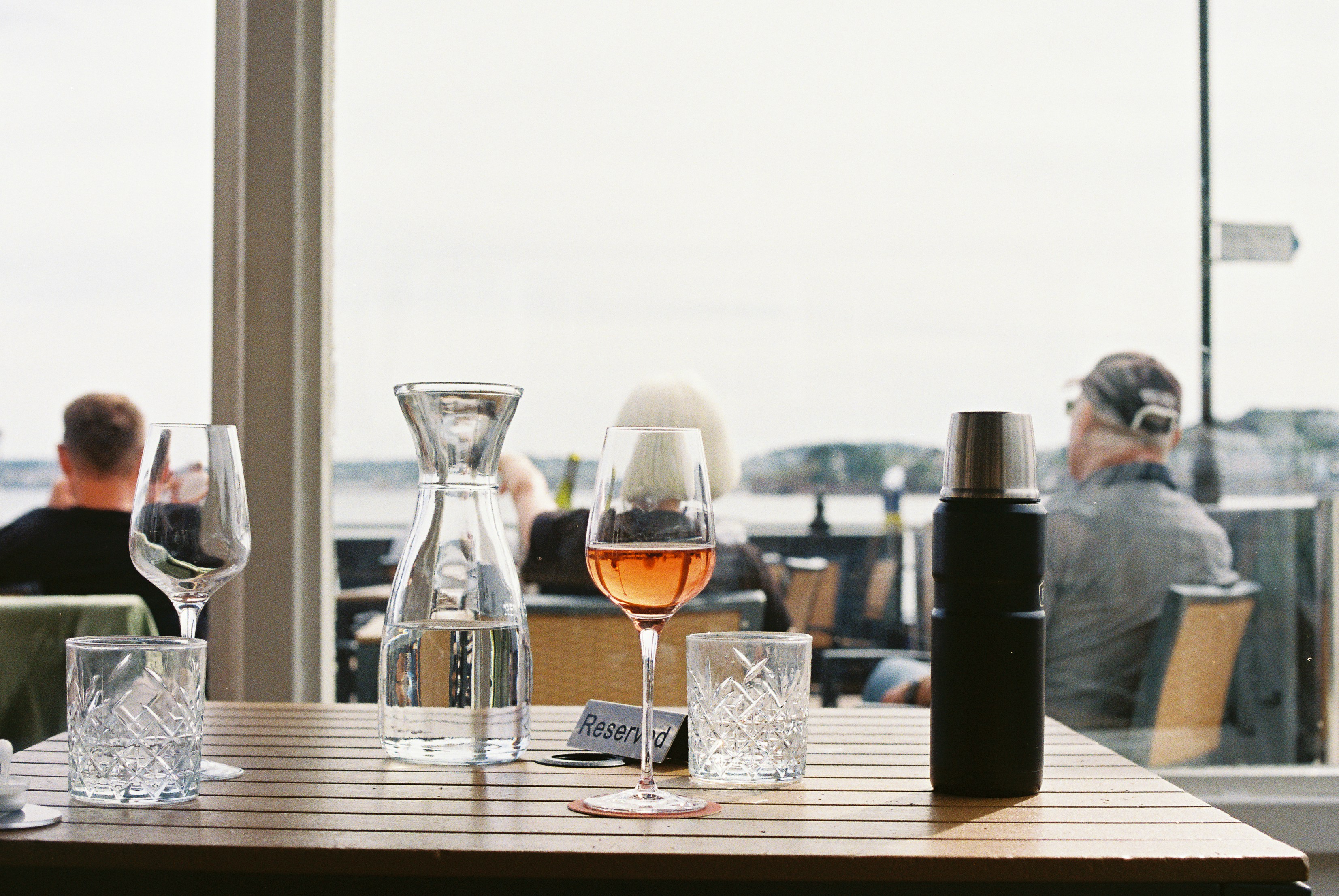Copa de vino rosado sobre una mesa con vistas a la orilla.