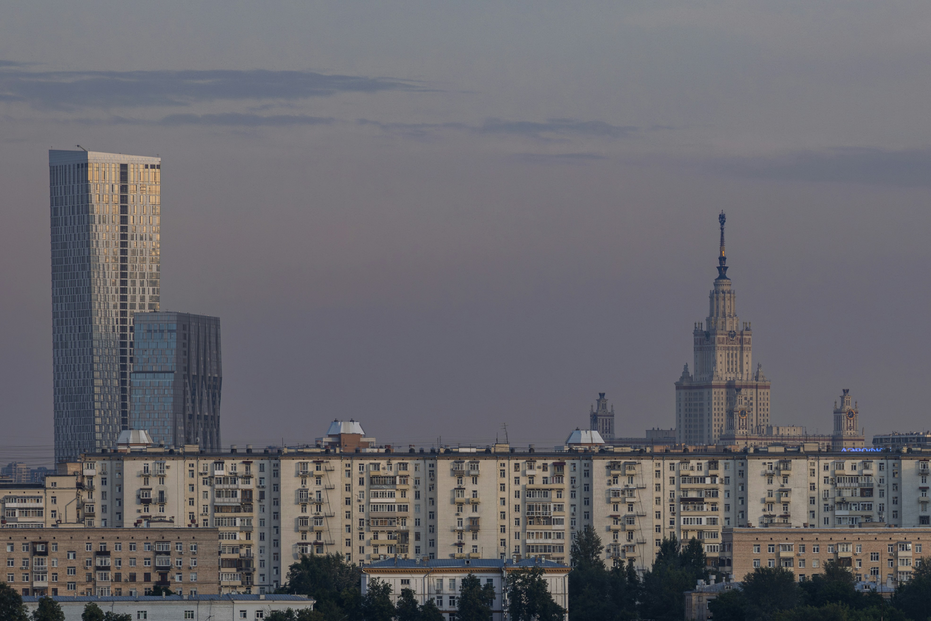 Cityscape at dusk with modern and historic buildings.