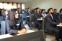 Students in uniforms listening attentively in a classroom.