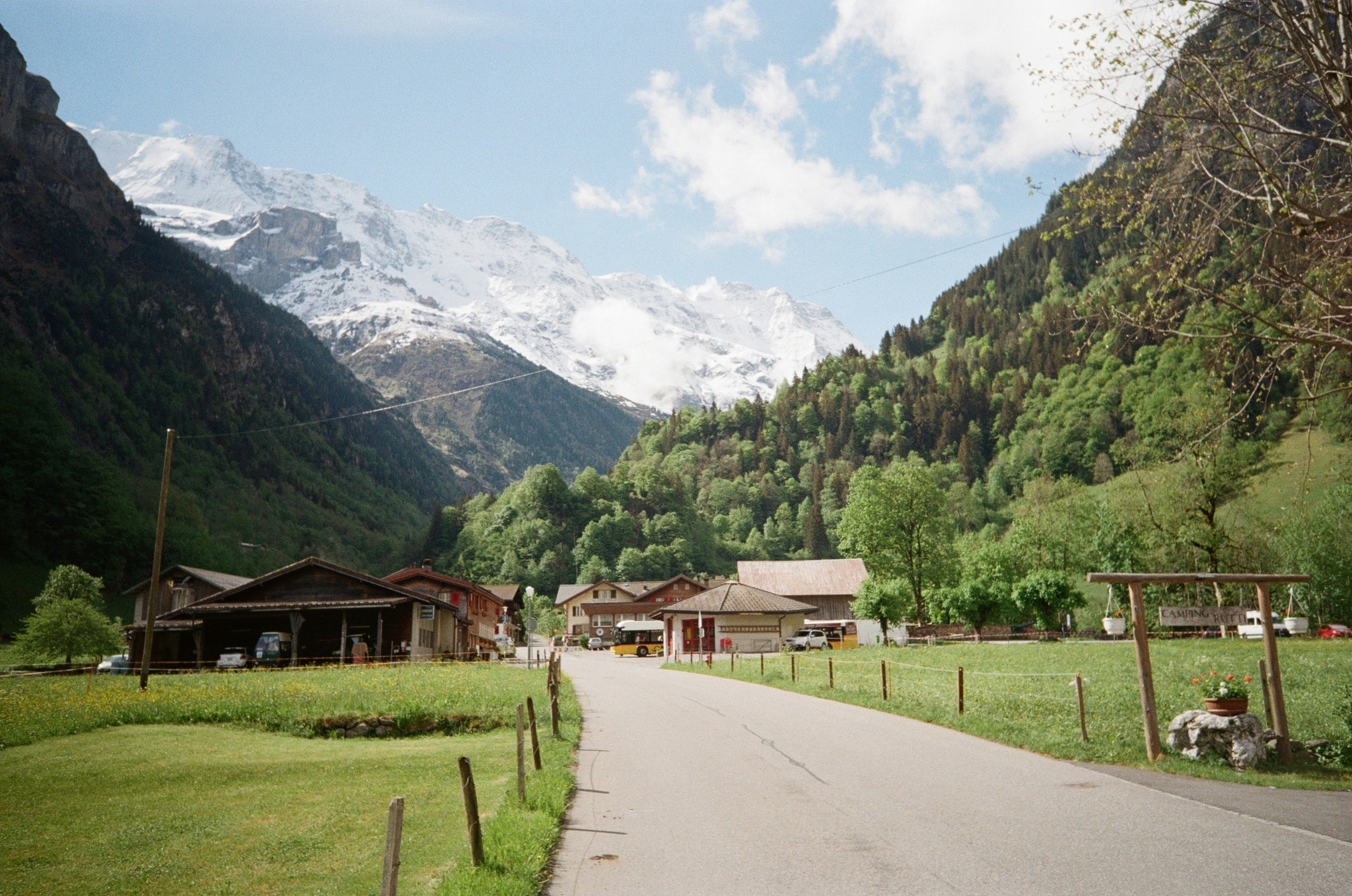 Malerisches Bergtal mit einer Straße und traditionellen Dorfgebäuden.