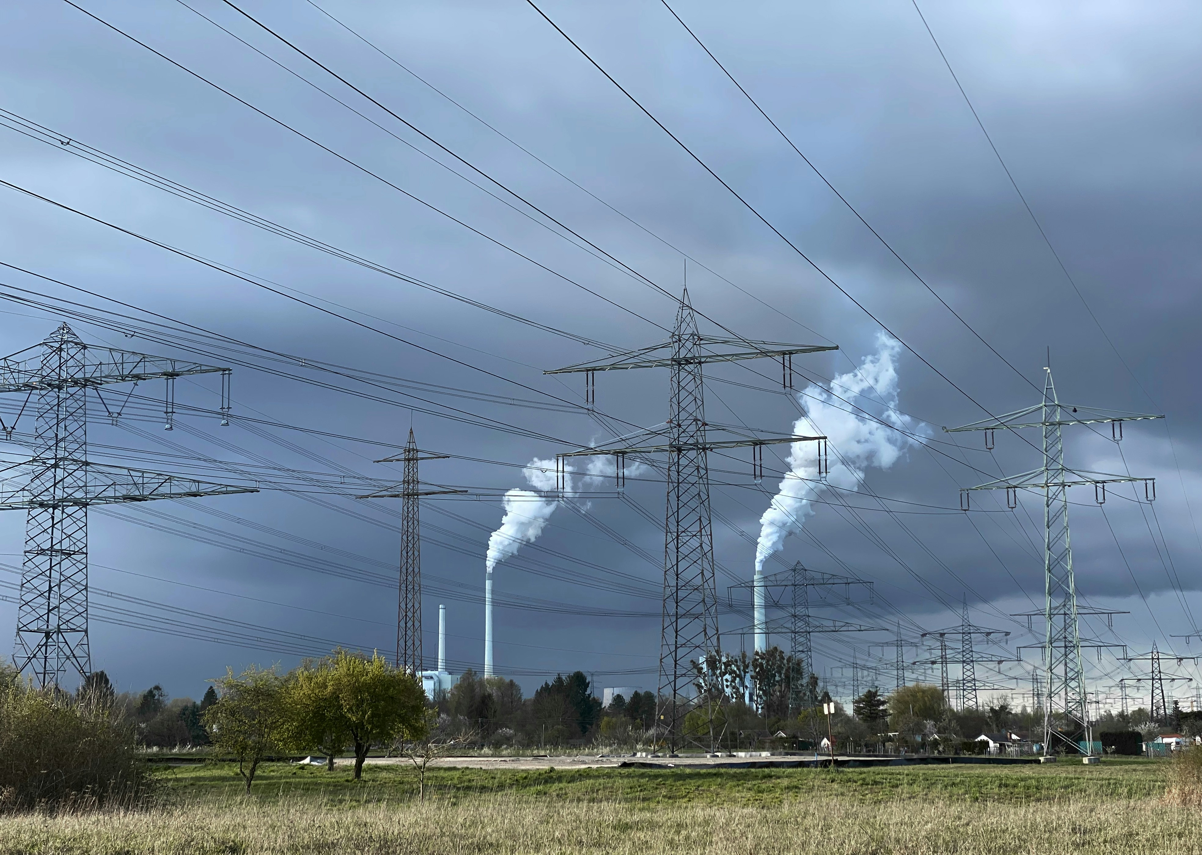 Power lines and smokestacks against a dark, cloudy sky.