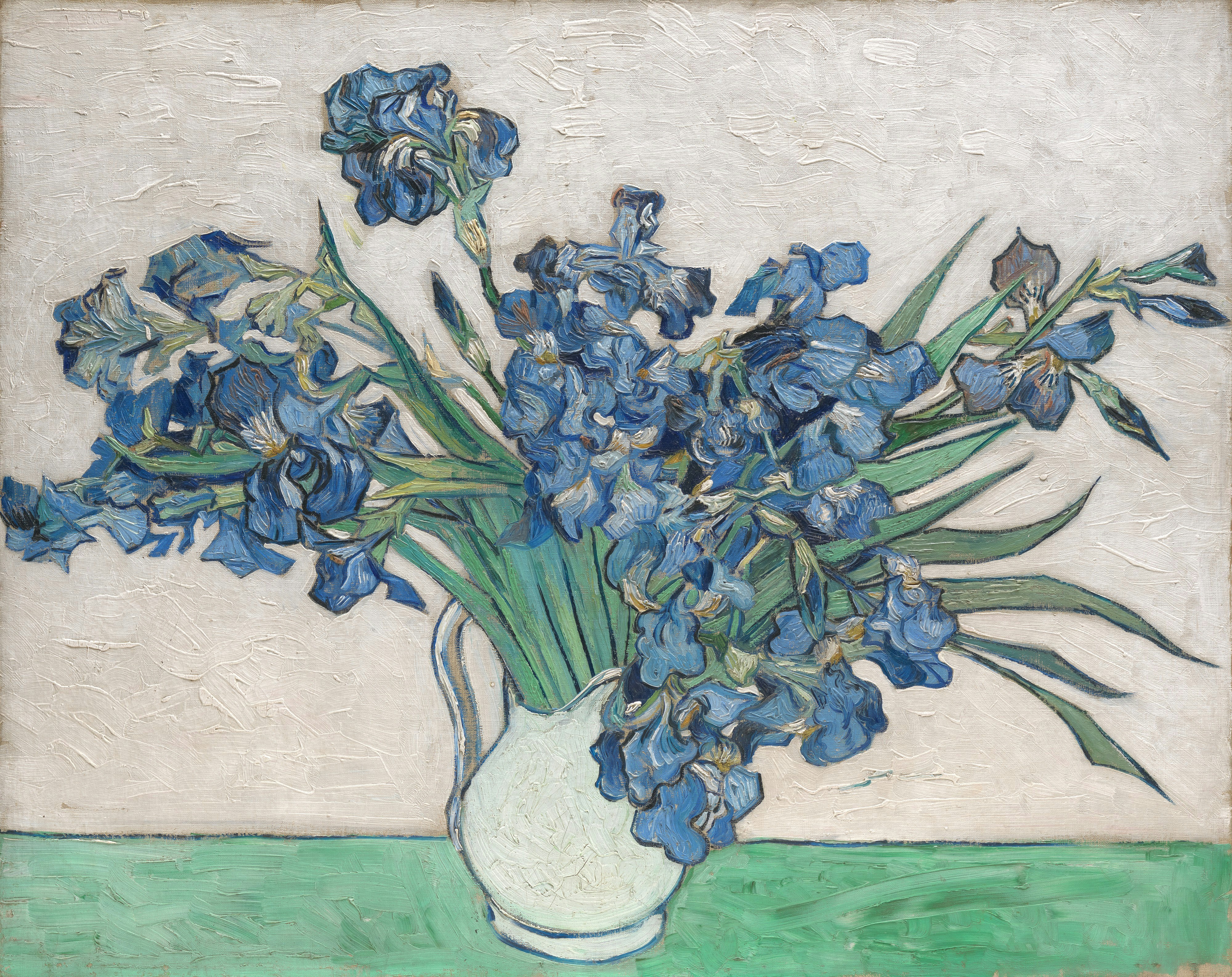 Blue irises in a white vase on a green table