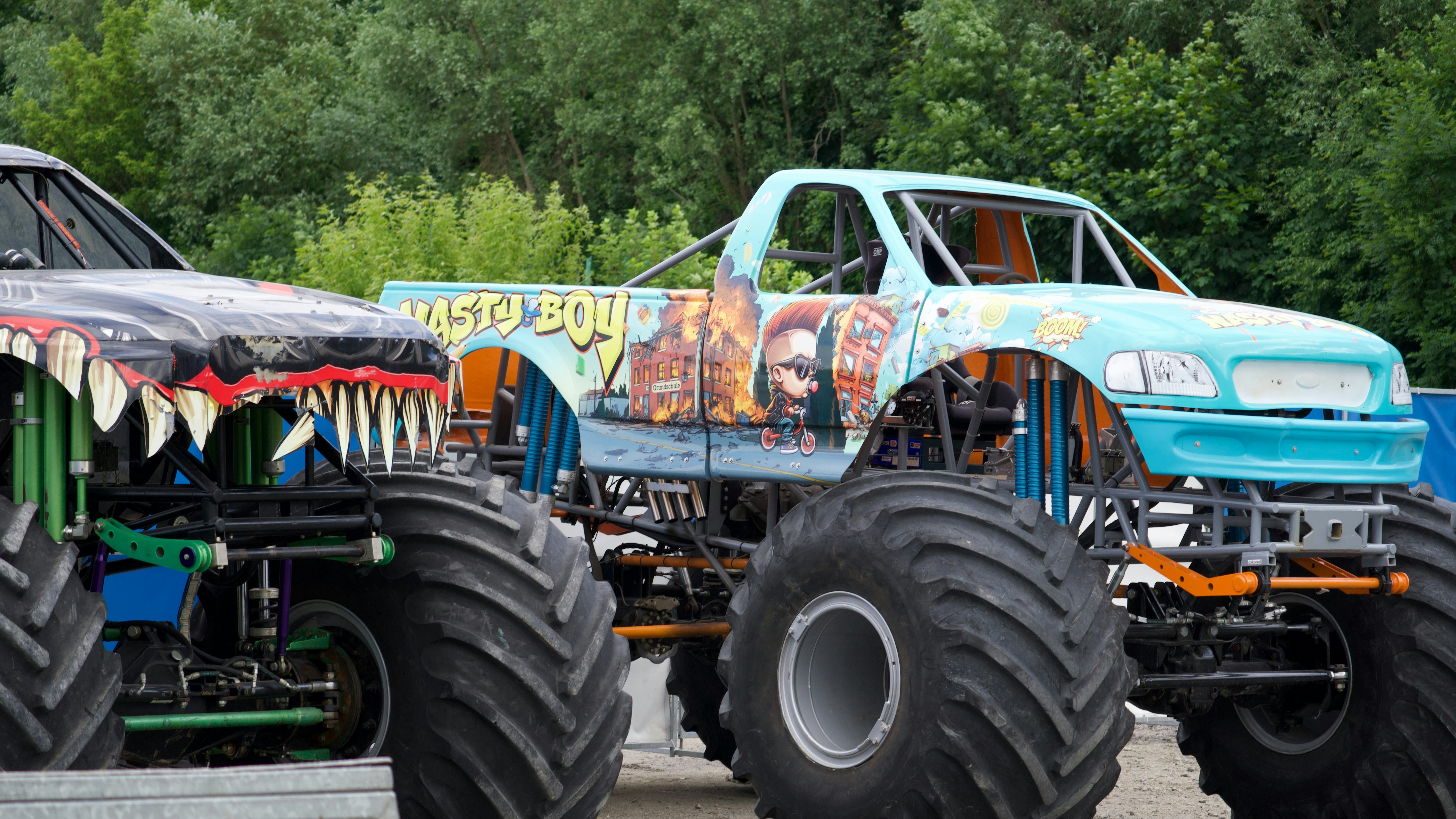 Two monster trucks with large tires parked outdoors.