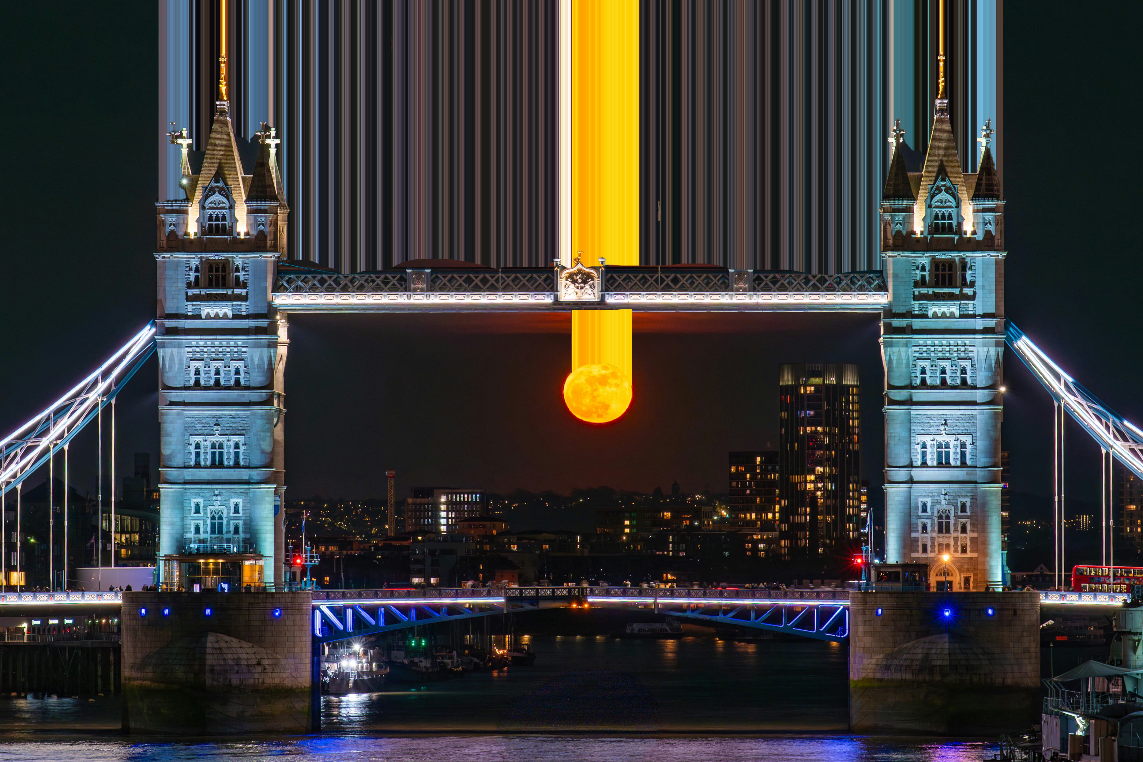 Orange moon perfectly framed by london's tower bridge at night.