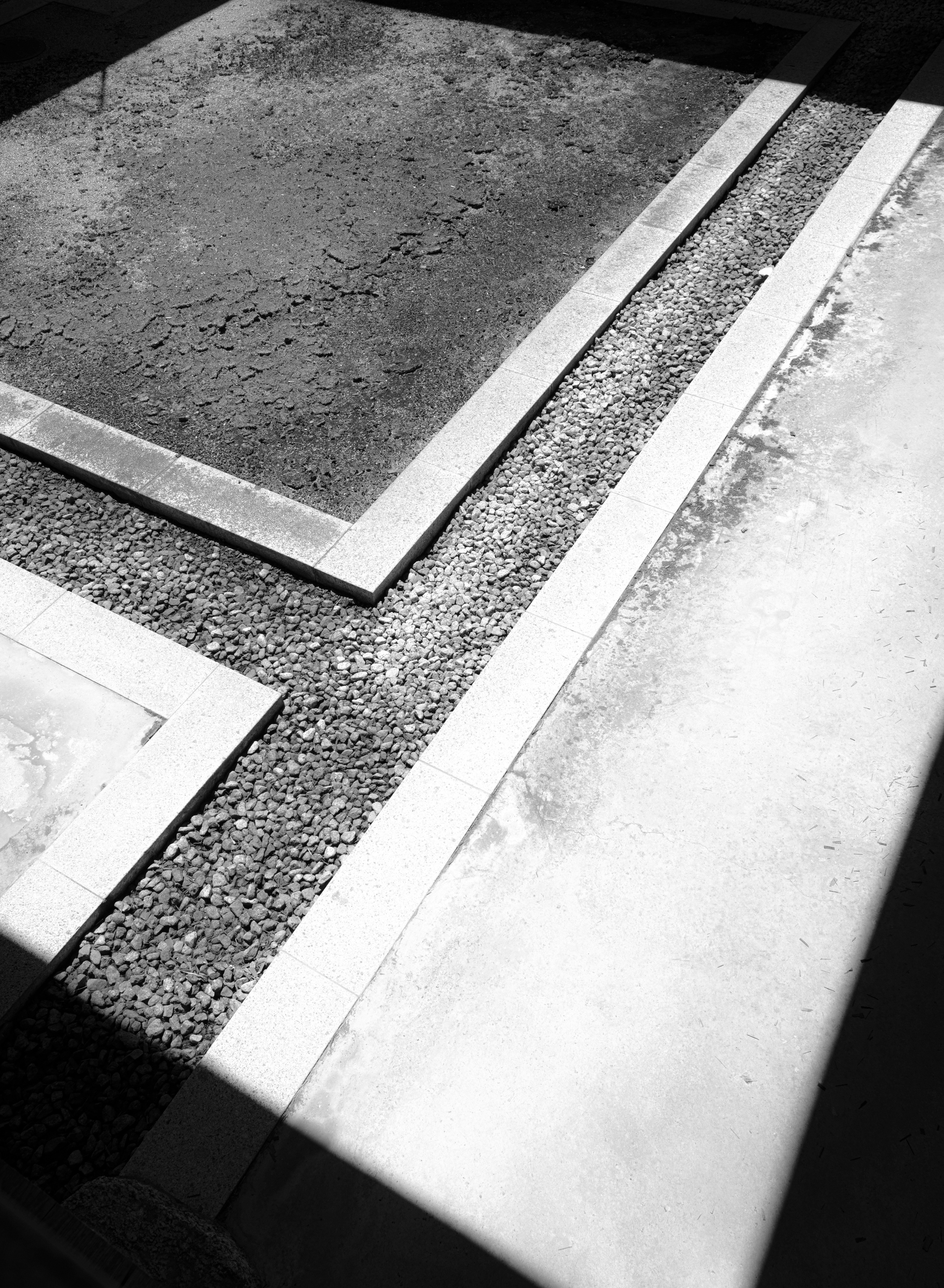 Geometric concrete and gravel patterns with a diagonal shadow.