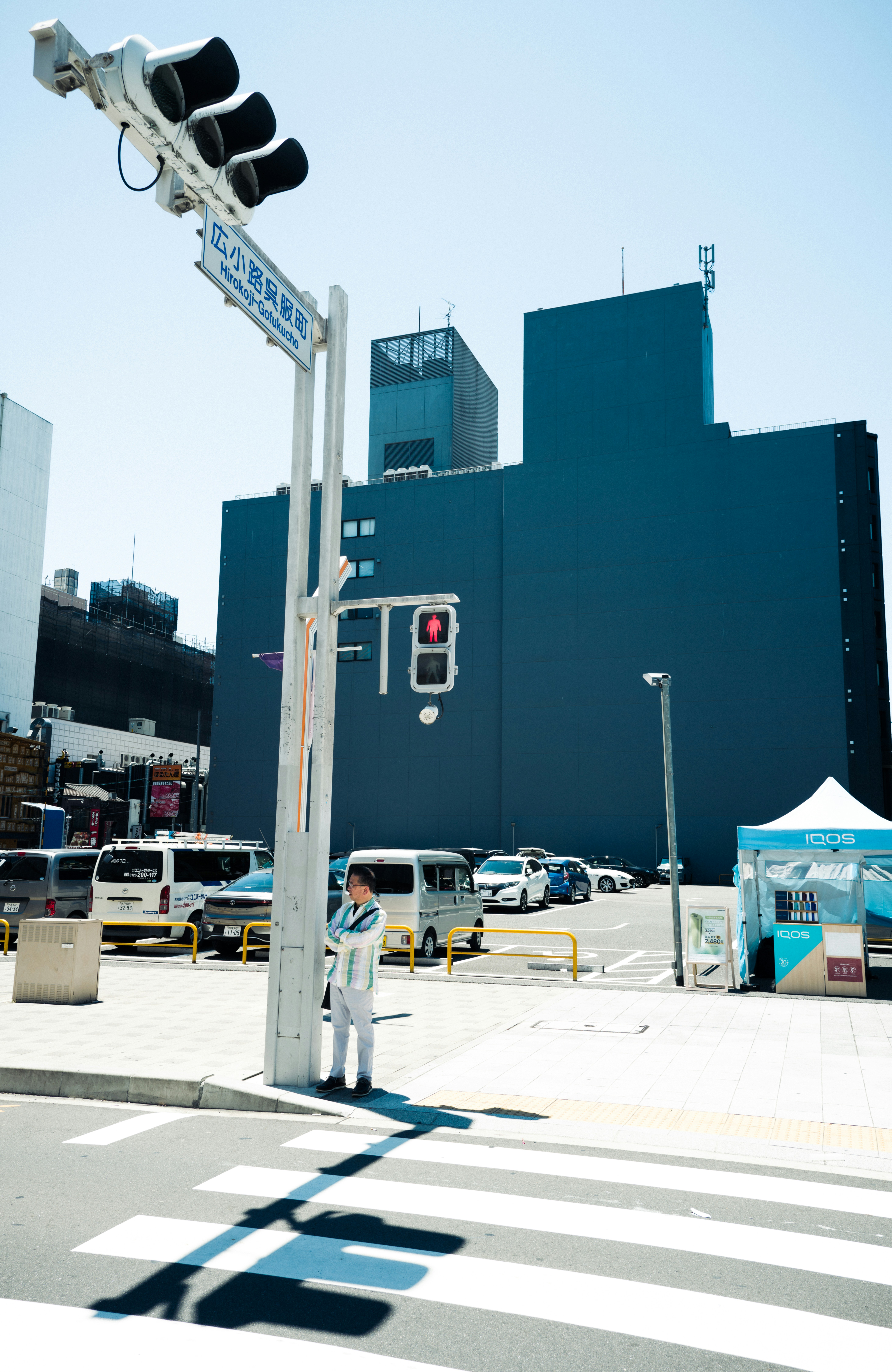 Man waits at crosswalk under a red traffic light.