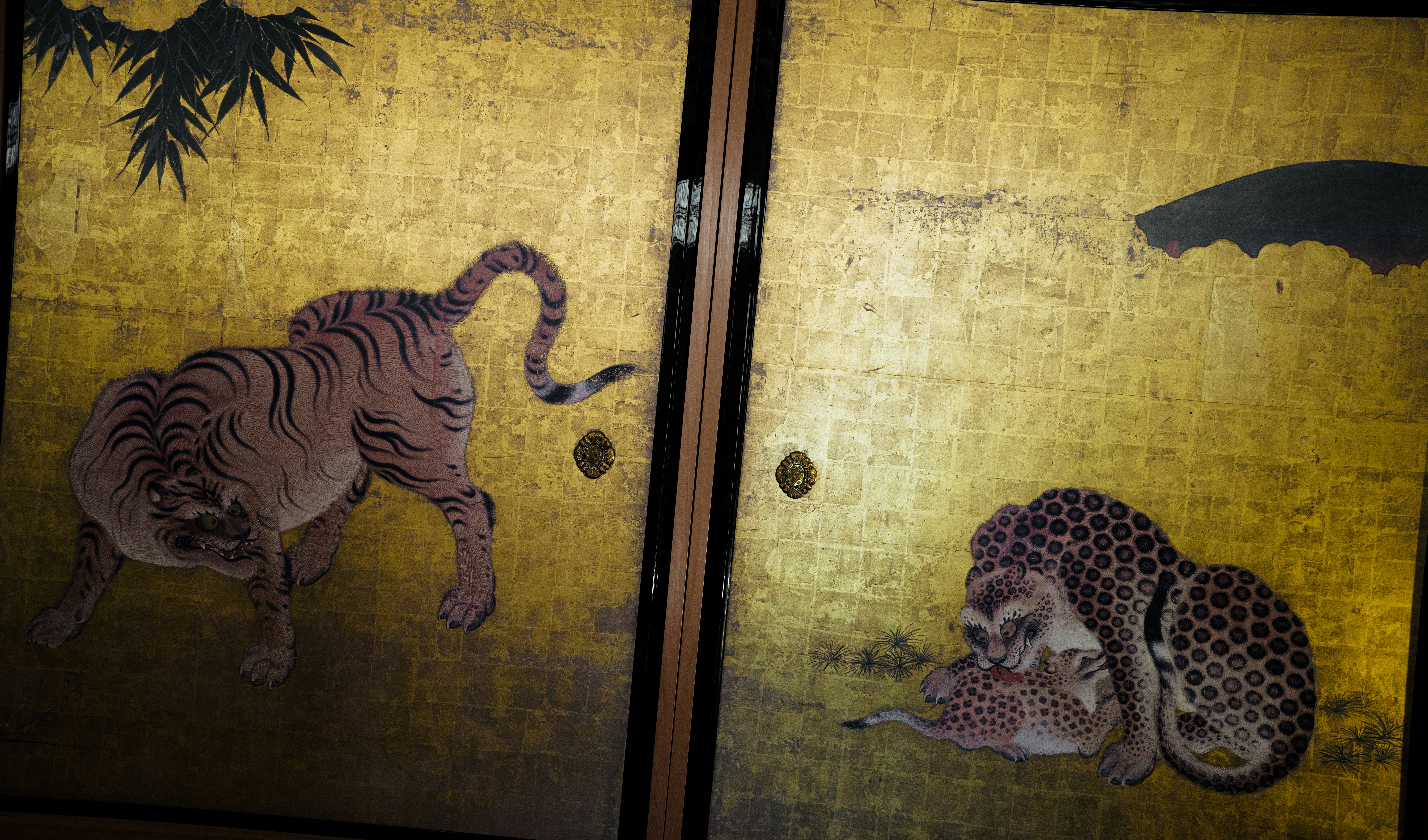 Golden screen with painted tigers and bamboo leaves.