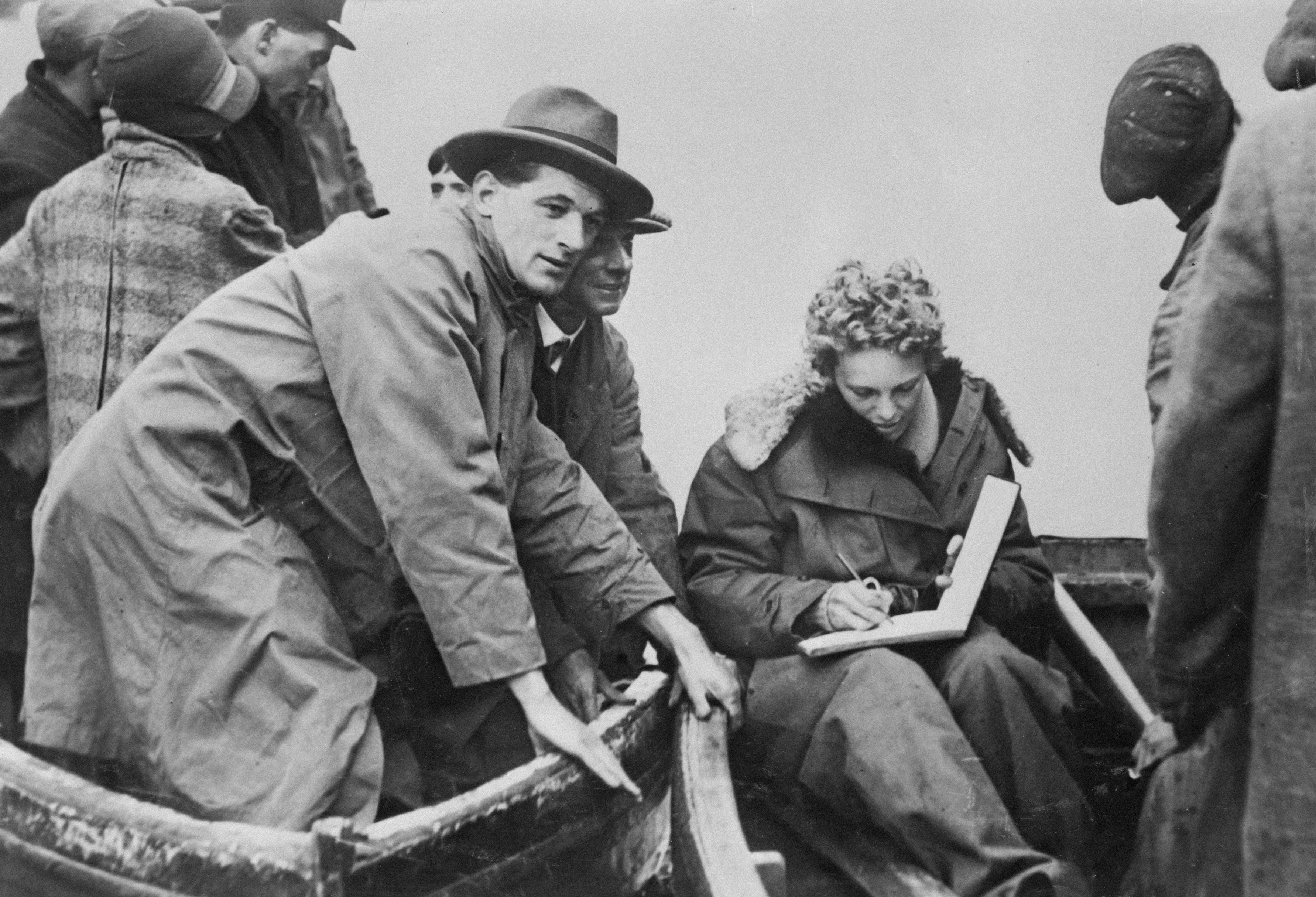 Frau, die mit einem Mann in einem Boot in ein Notizbuch schreibt.