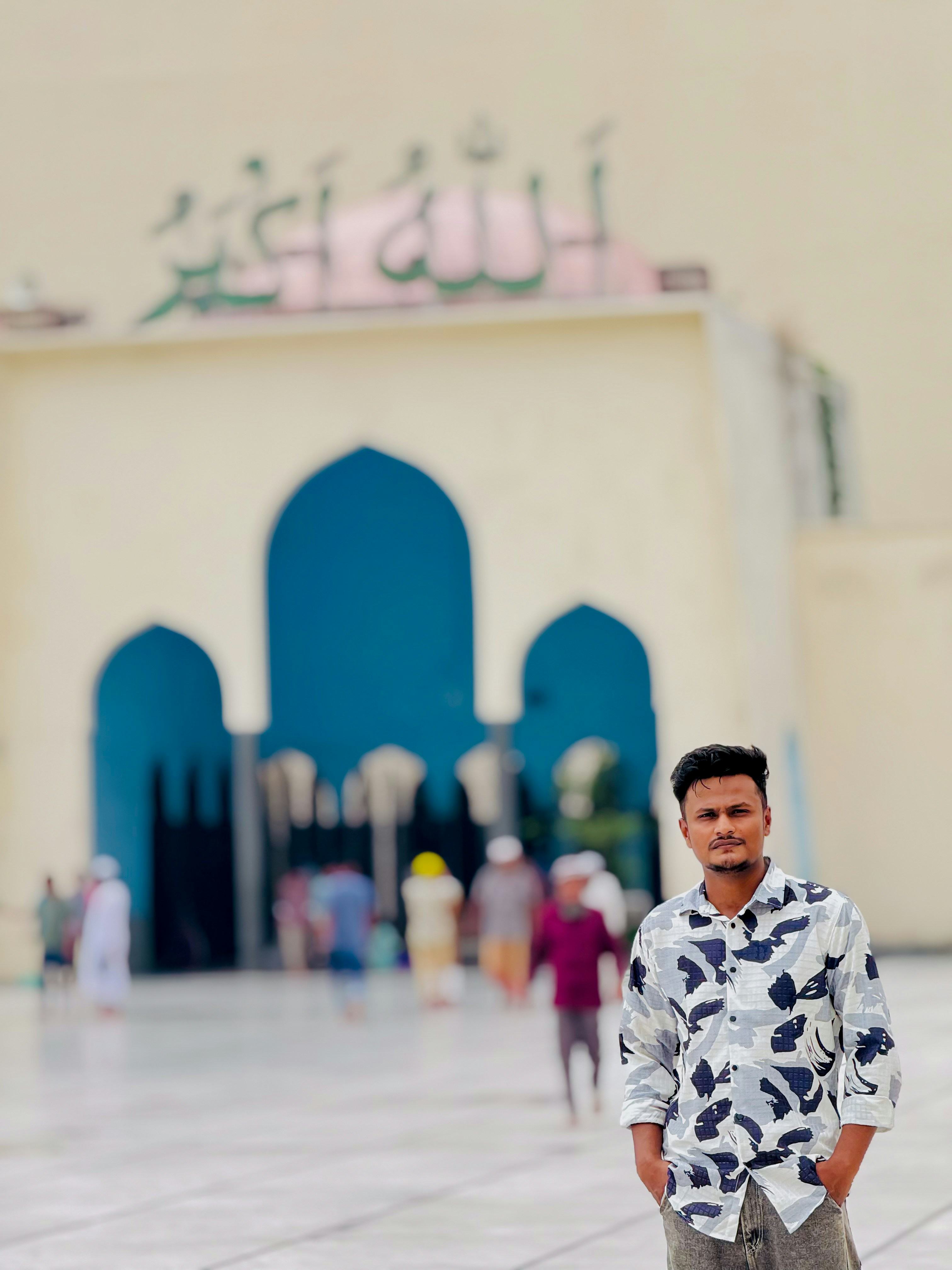 Seorang pemuda berdiri di depan pintu masuk masjid.