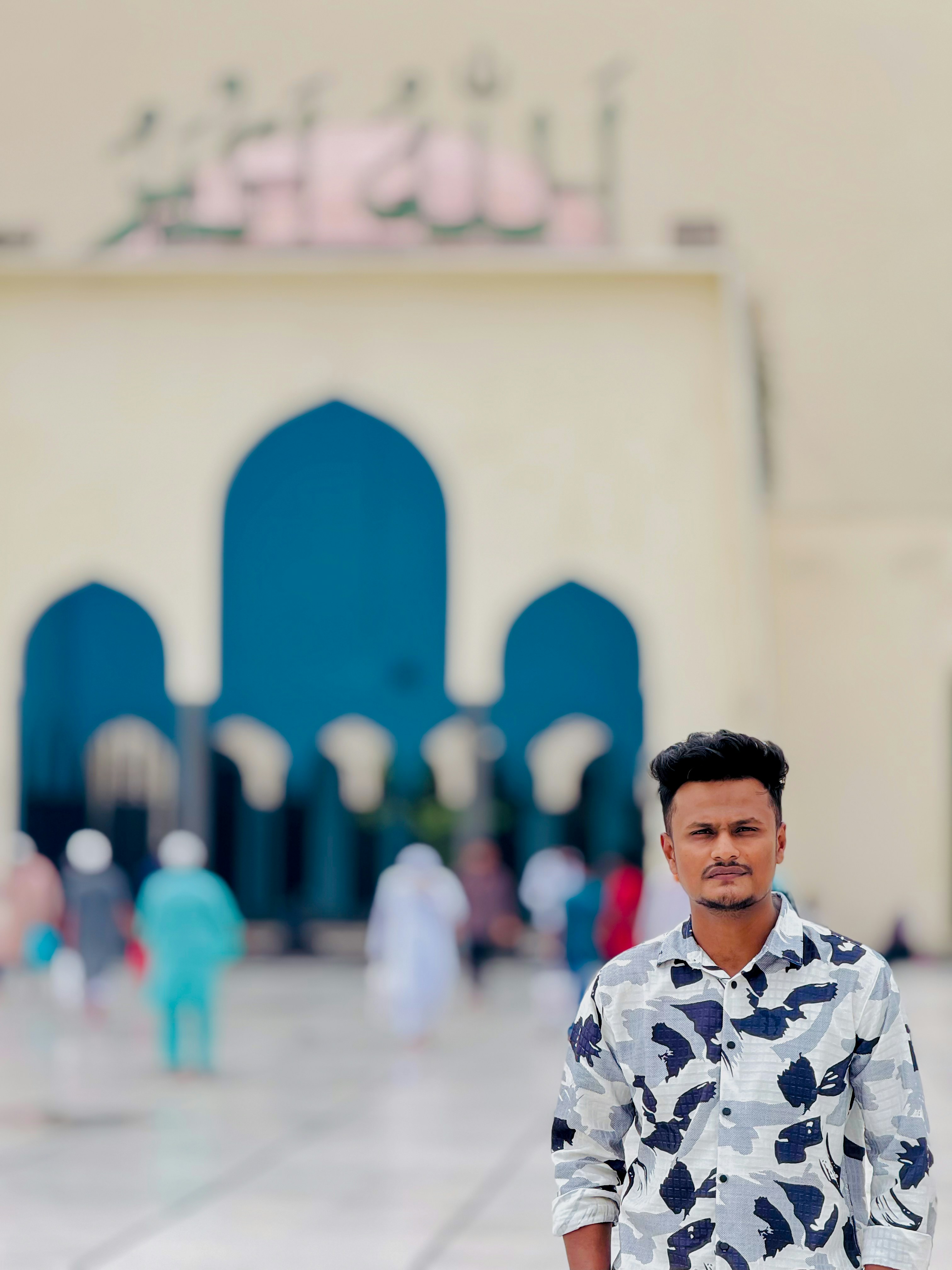 Seorang pemuda berdiri di depan sebuah masjid.