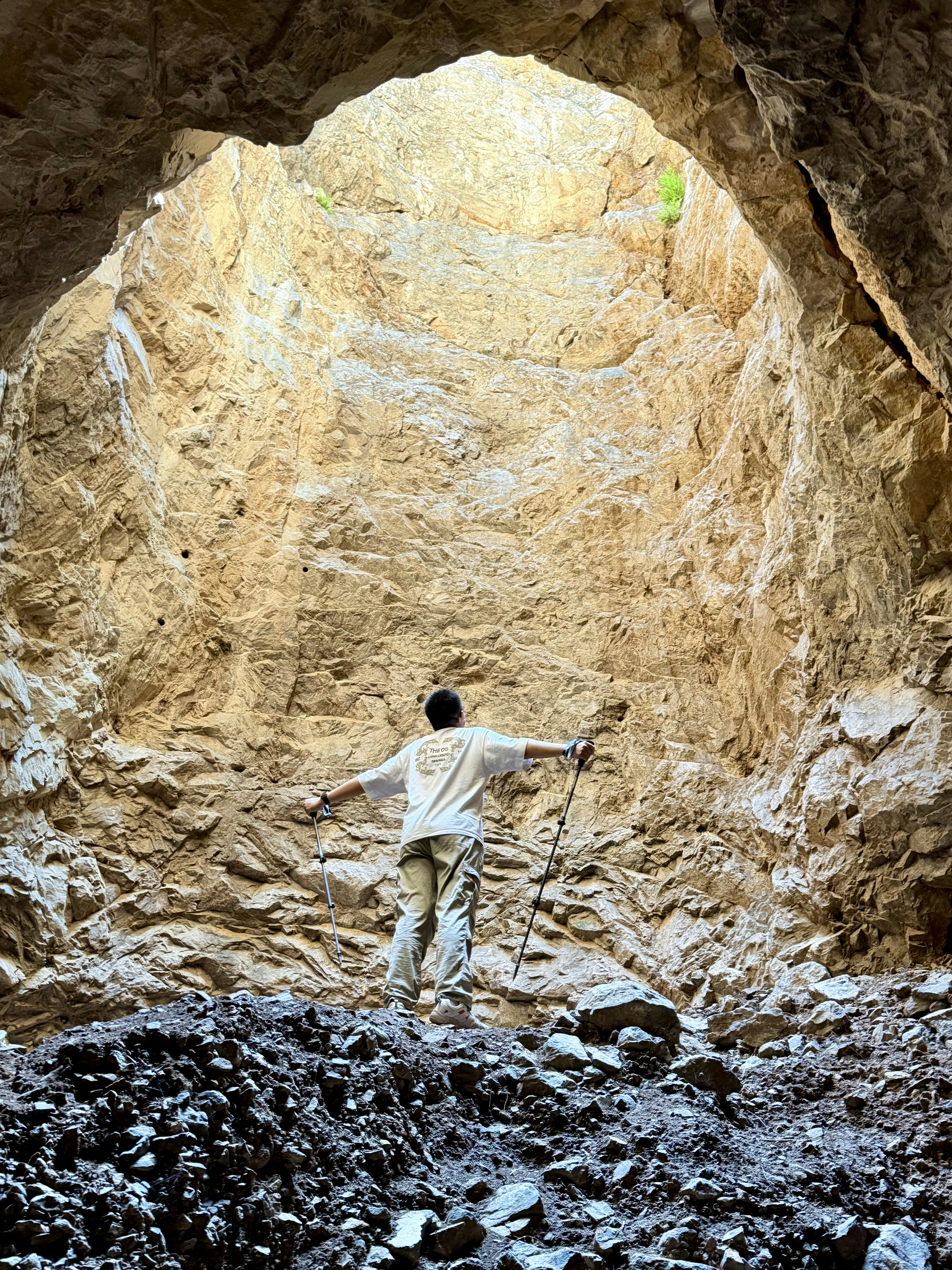 Person looking up at light from a deep cave opening.