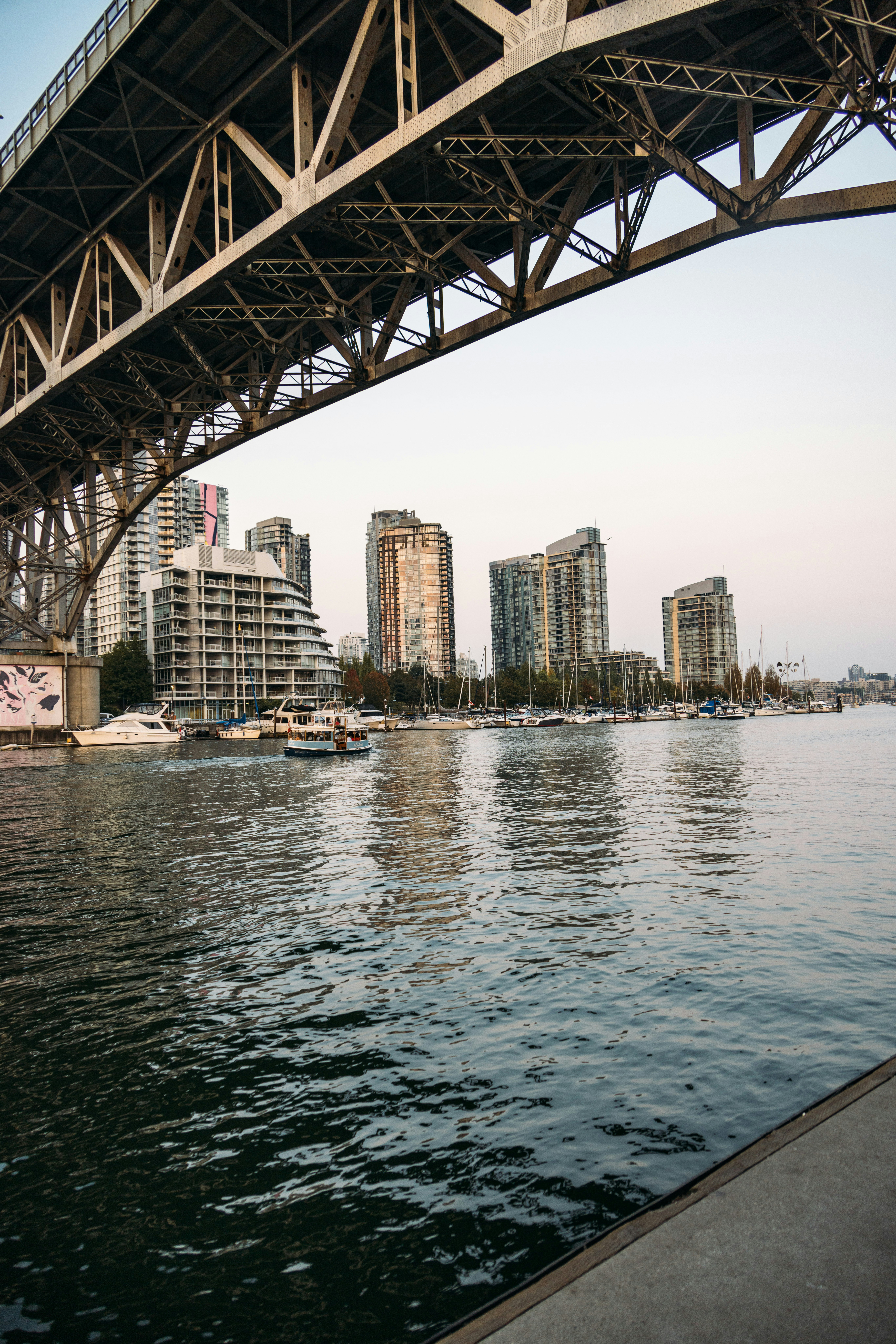 City skyline, boats, and bridge over water.