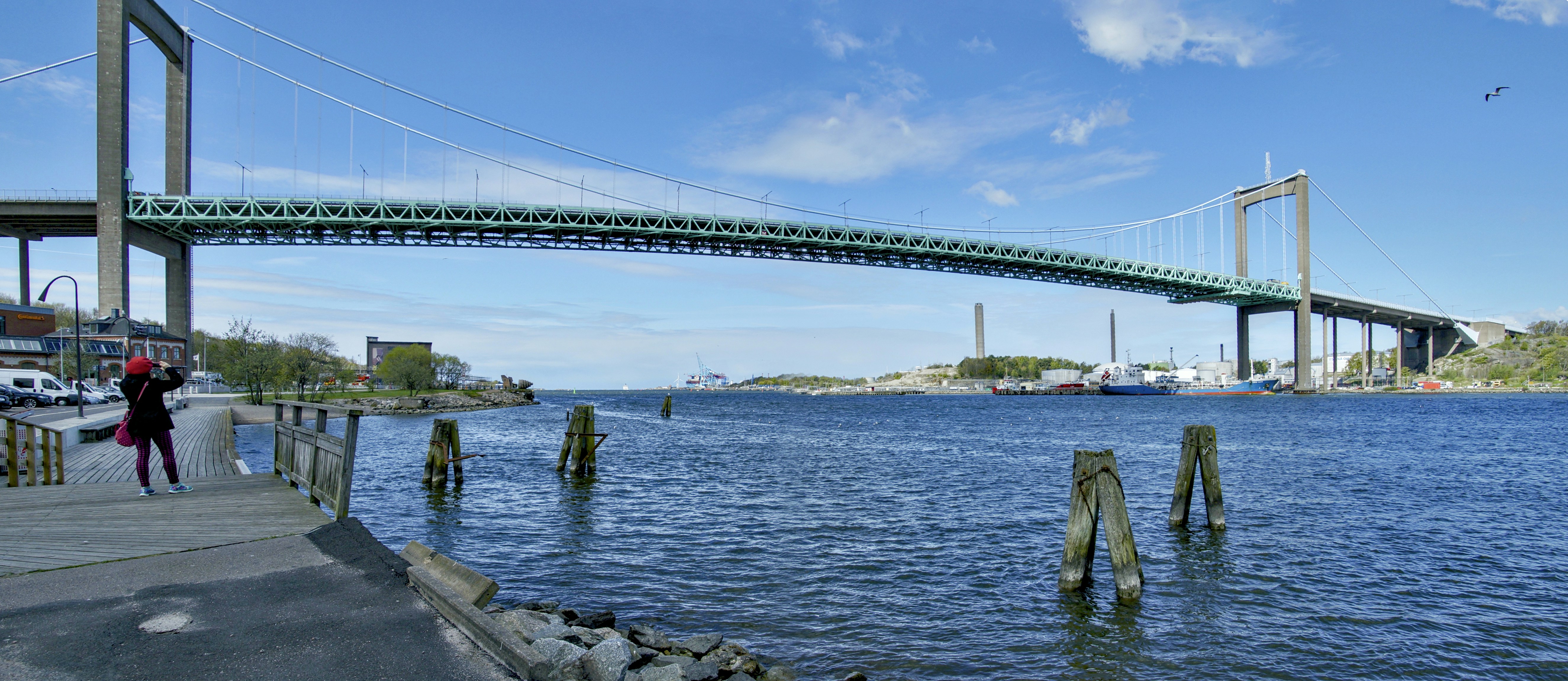 Grand pont suspendu au-dessus d’une eau bleue et une personne.