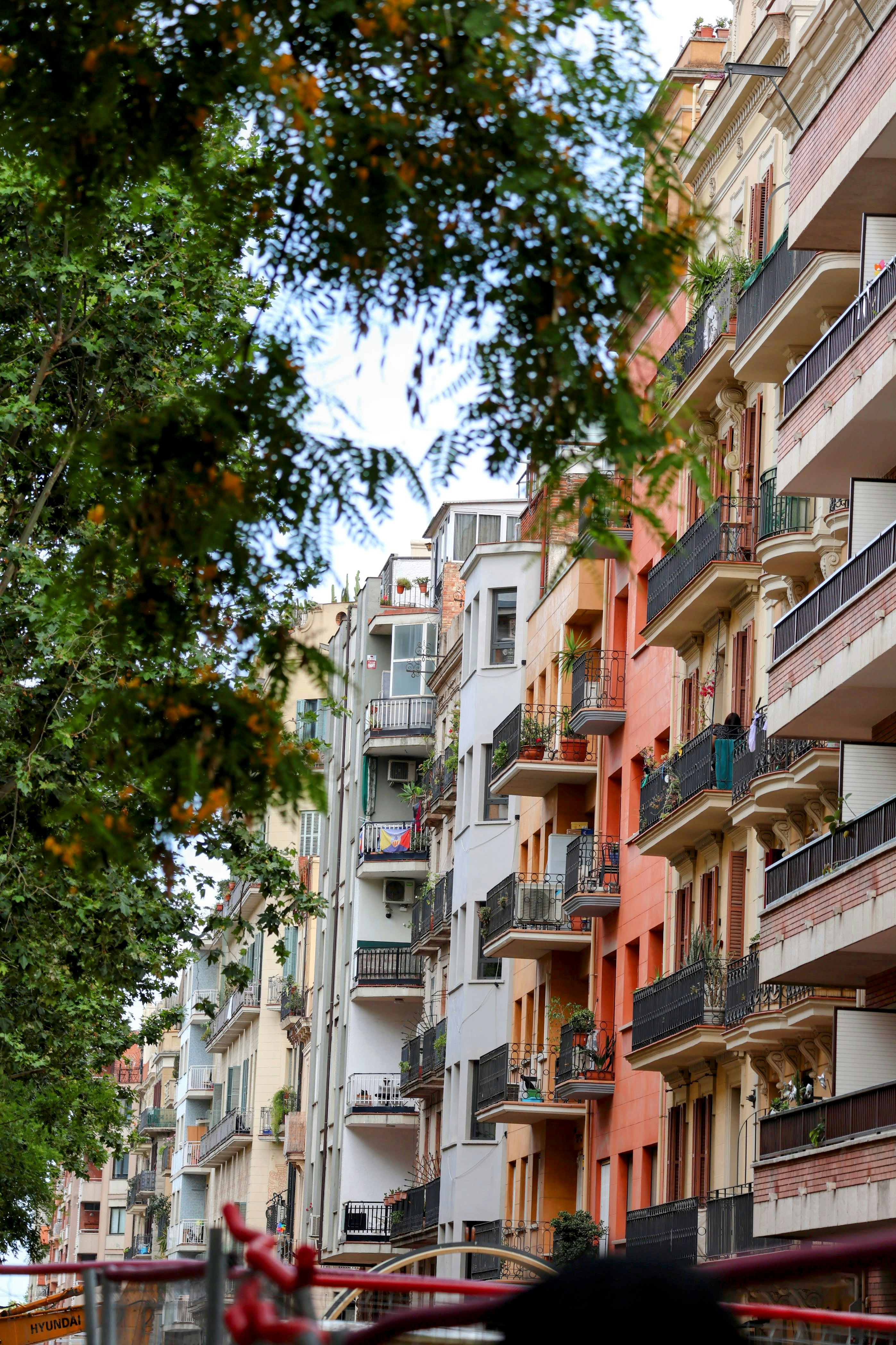 Colorful residential buildings with balconies framed by green trees.