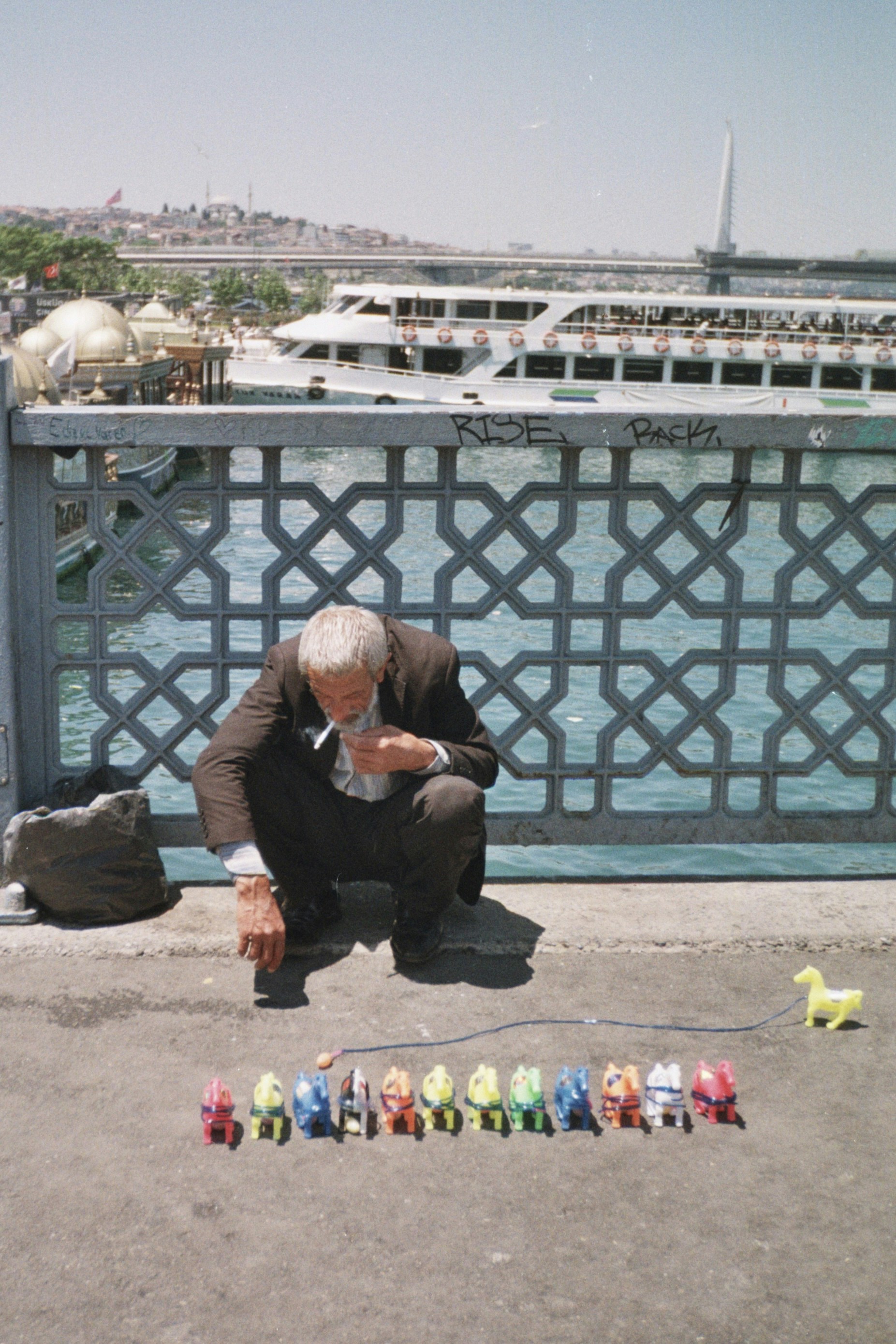 Elderly man playing with colorful toy cars on a bridge.