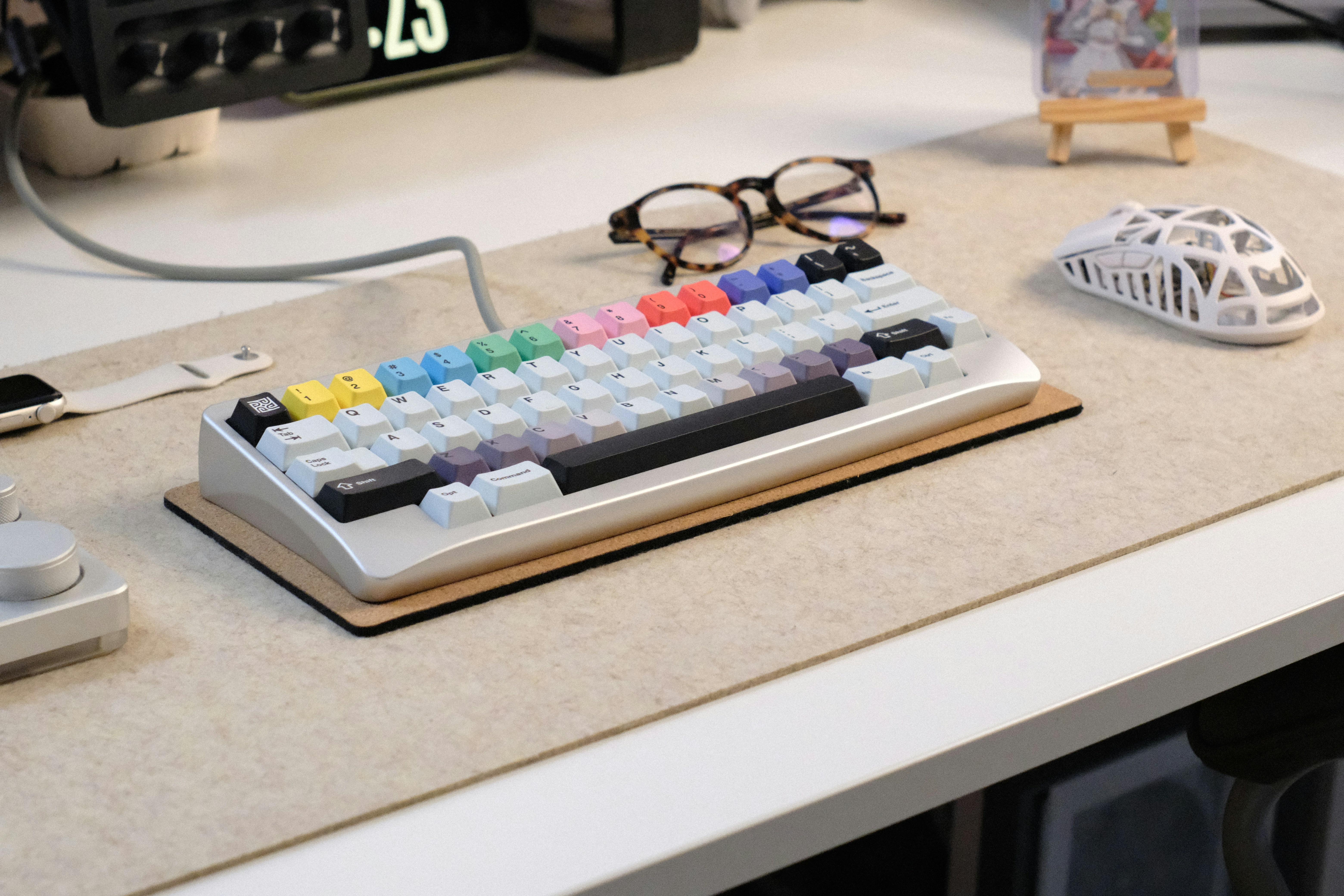 Mechanical keyboard, glasses, and mouse on a beige desk mat.