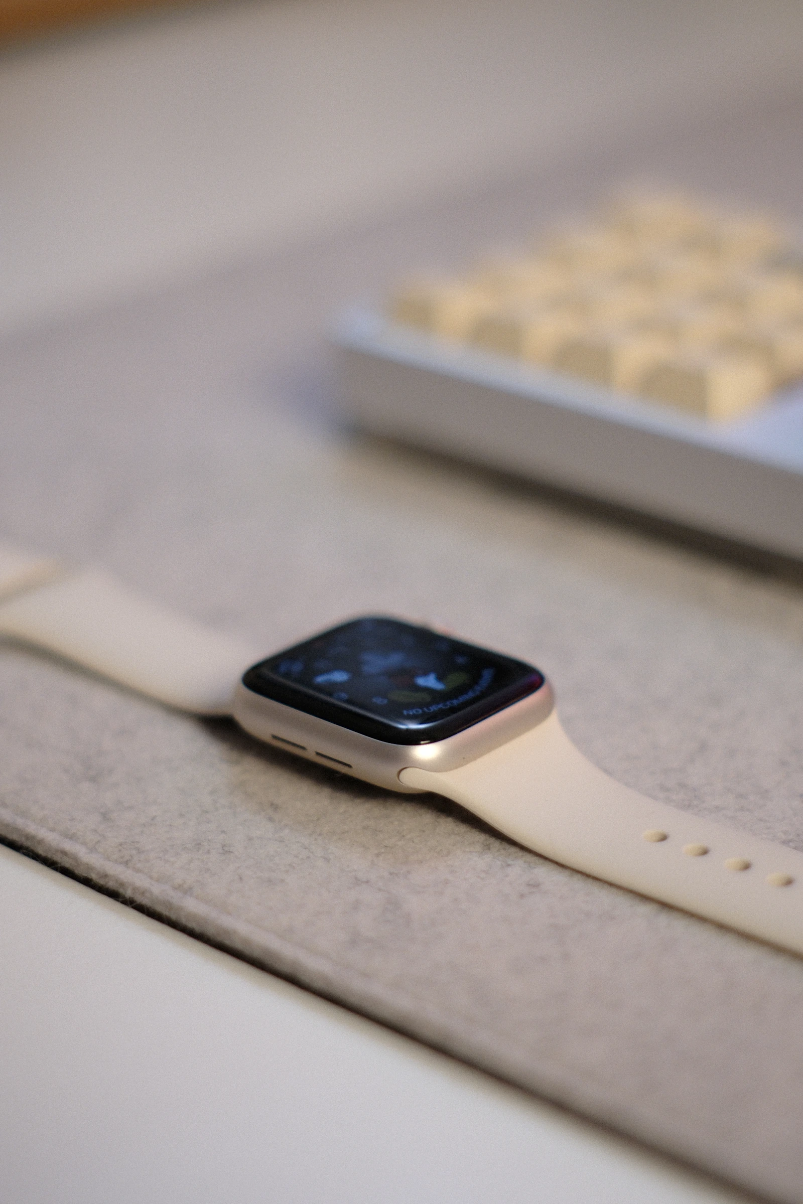 Modern smartwatch with a cream band on a felt desk mat