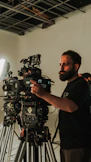 Bearded man adjusts a professional film camera in a studio