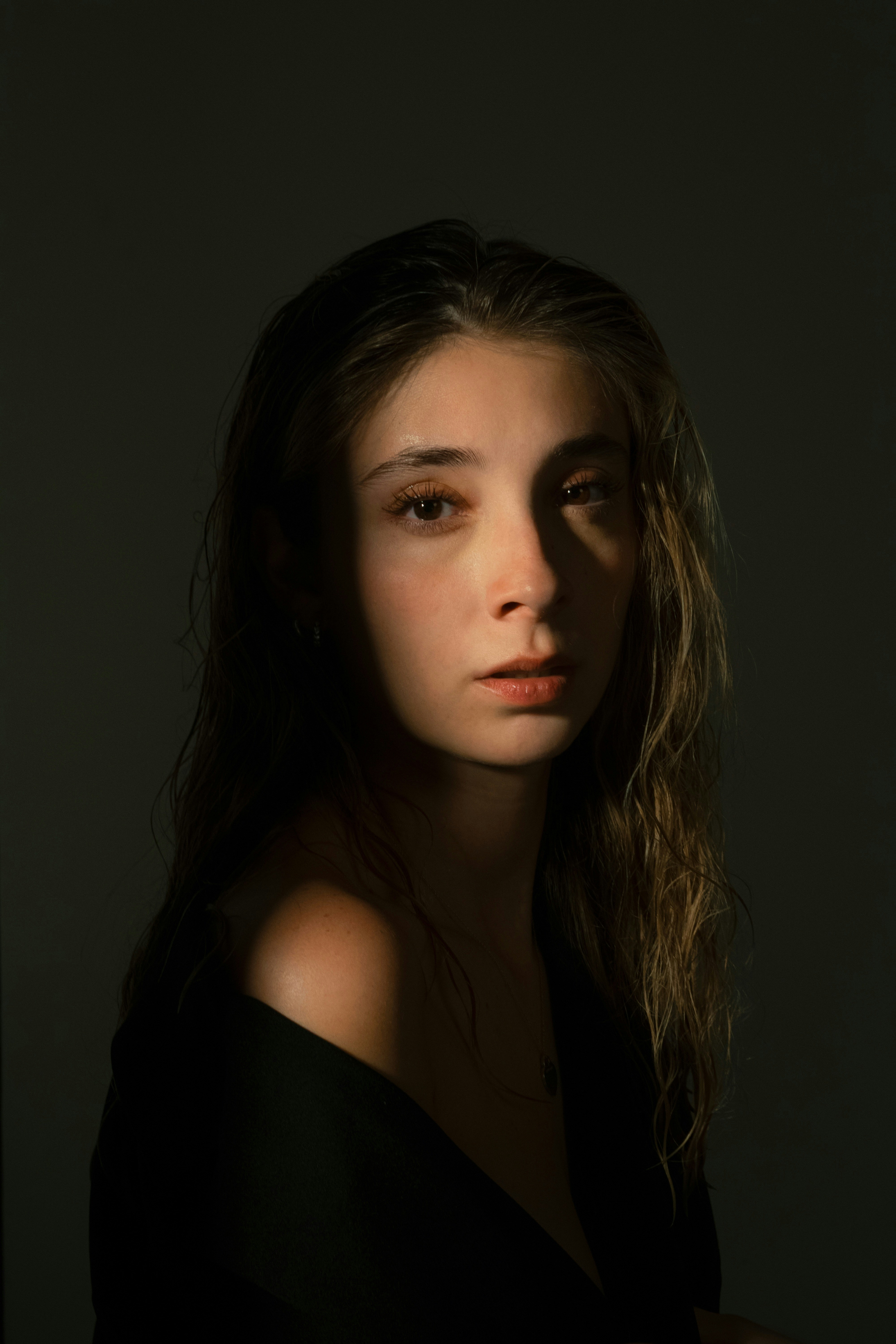 A young woman's face dramatically lit in shadow