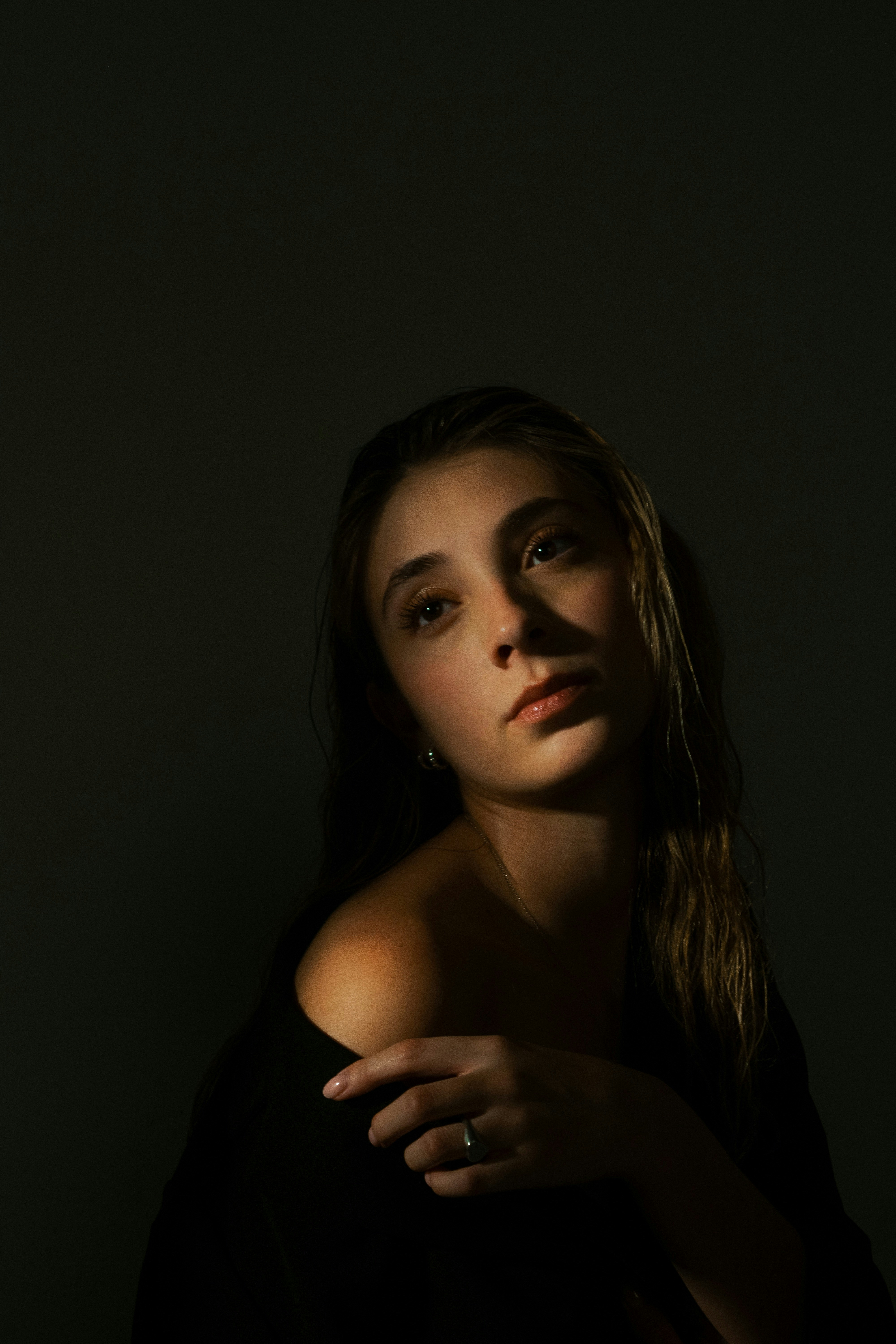 Dramatic lighting illuminates a young woman looking upwards in shadows