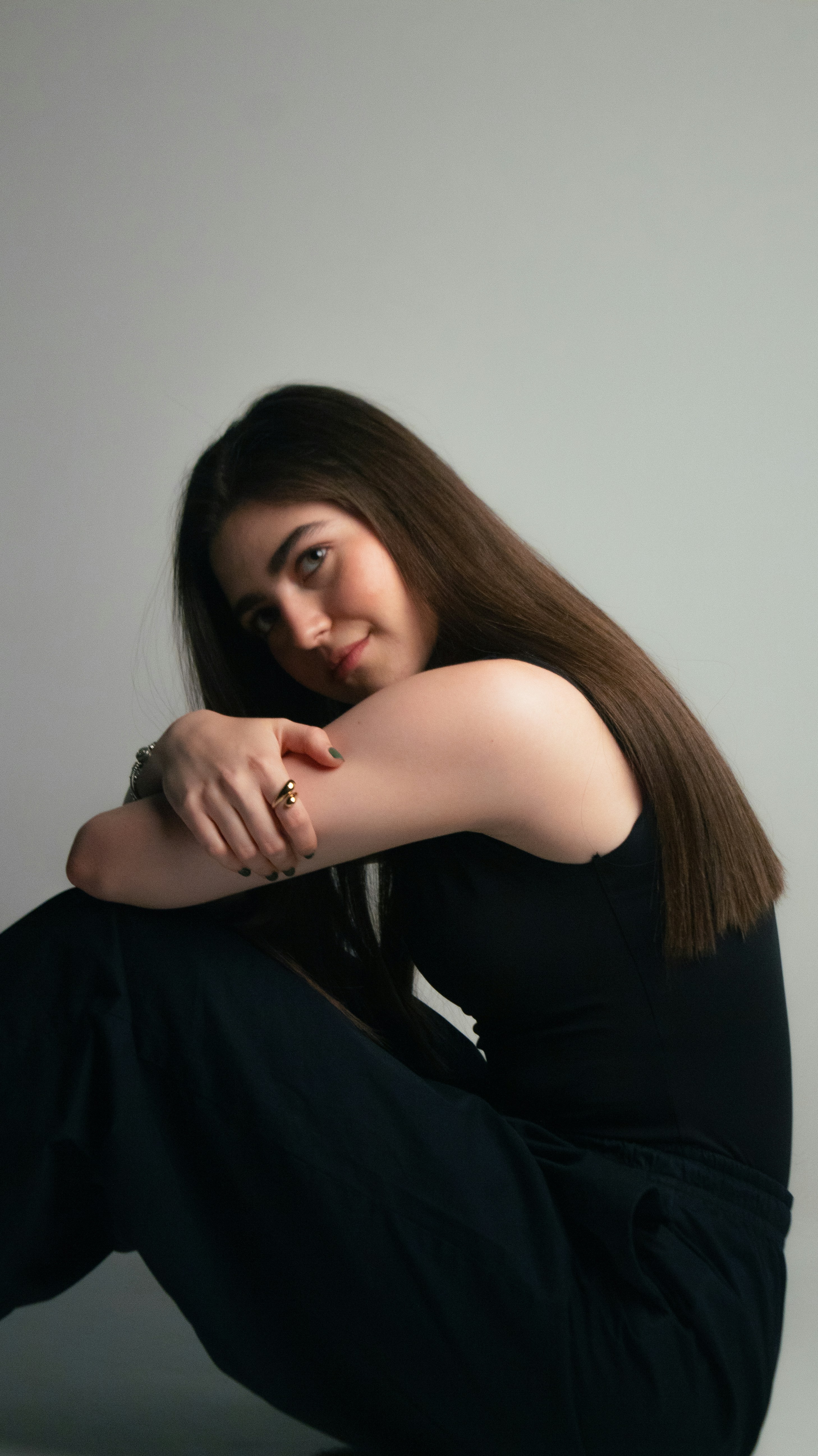Young woman in black sitting, looking at the camera
