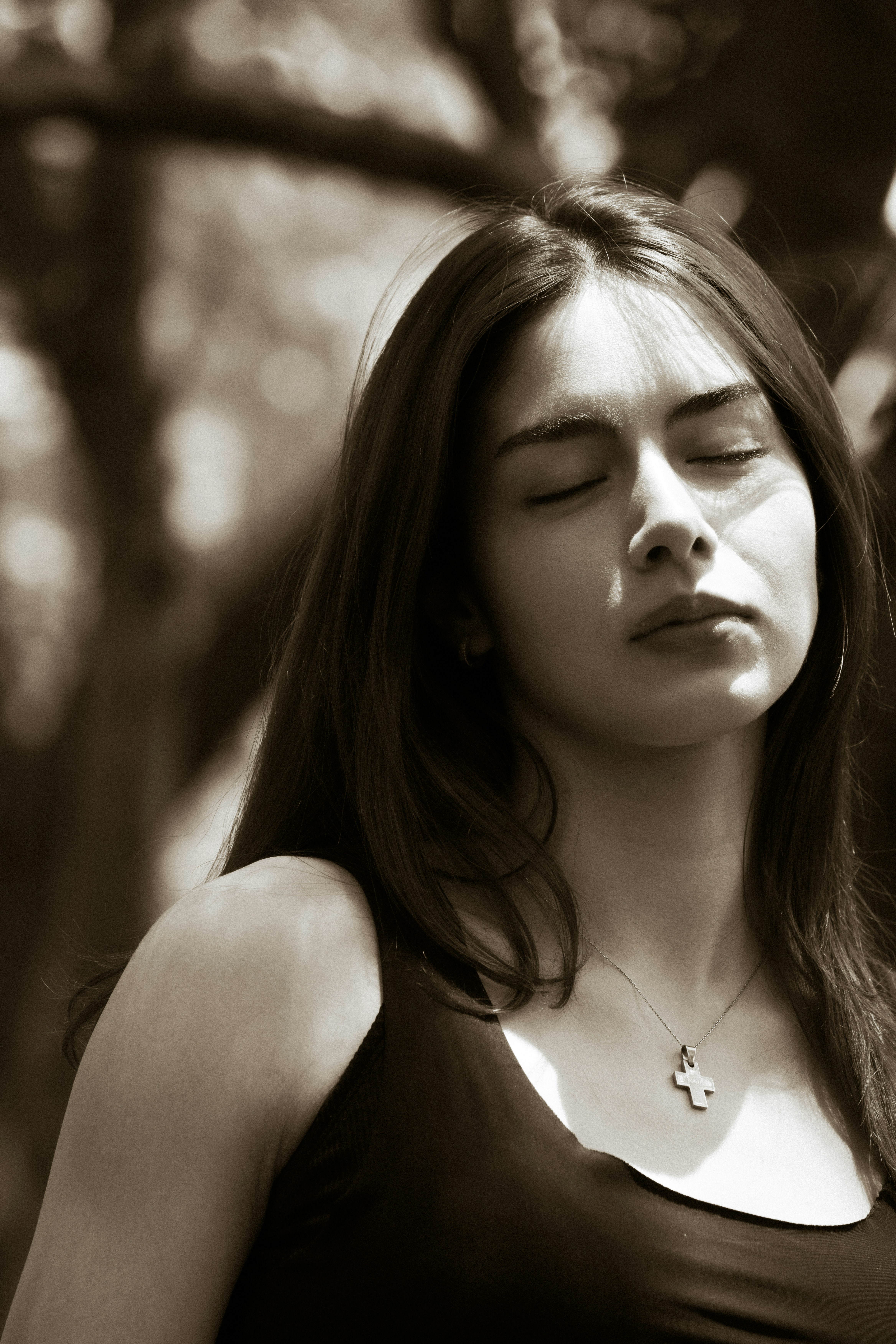 Serene young woman with closed eyes in dappled light
