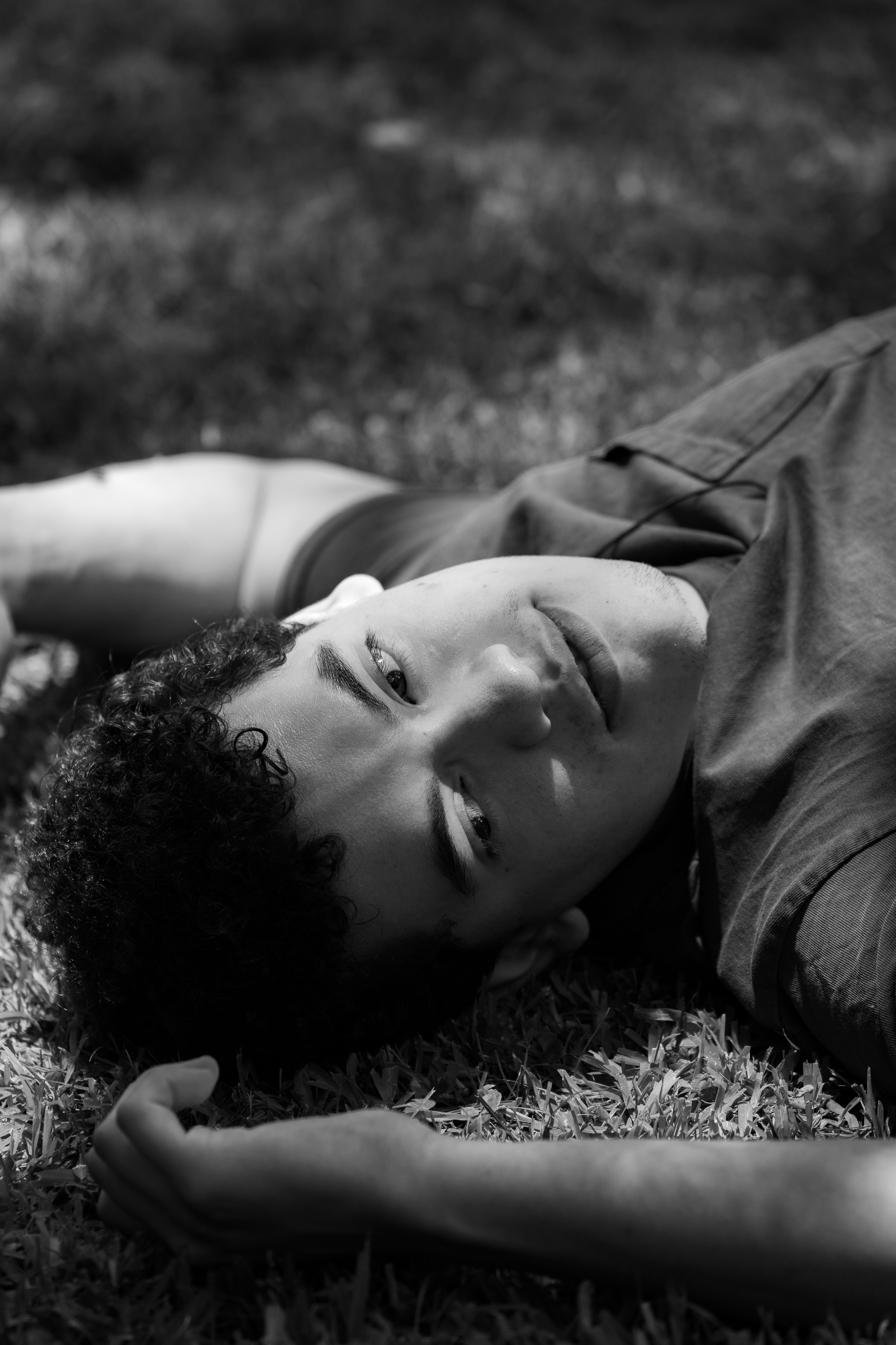 A young man lies on grass in black and white