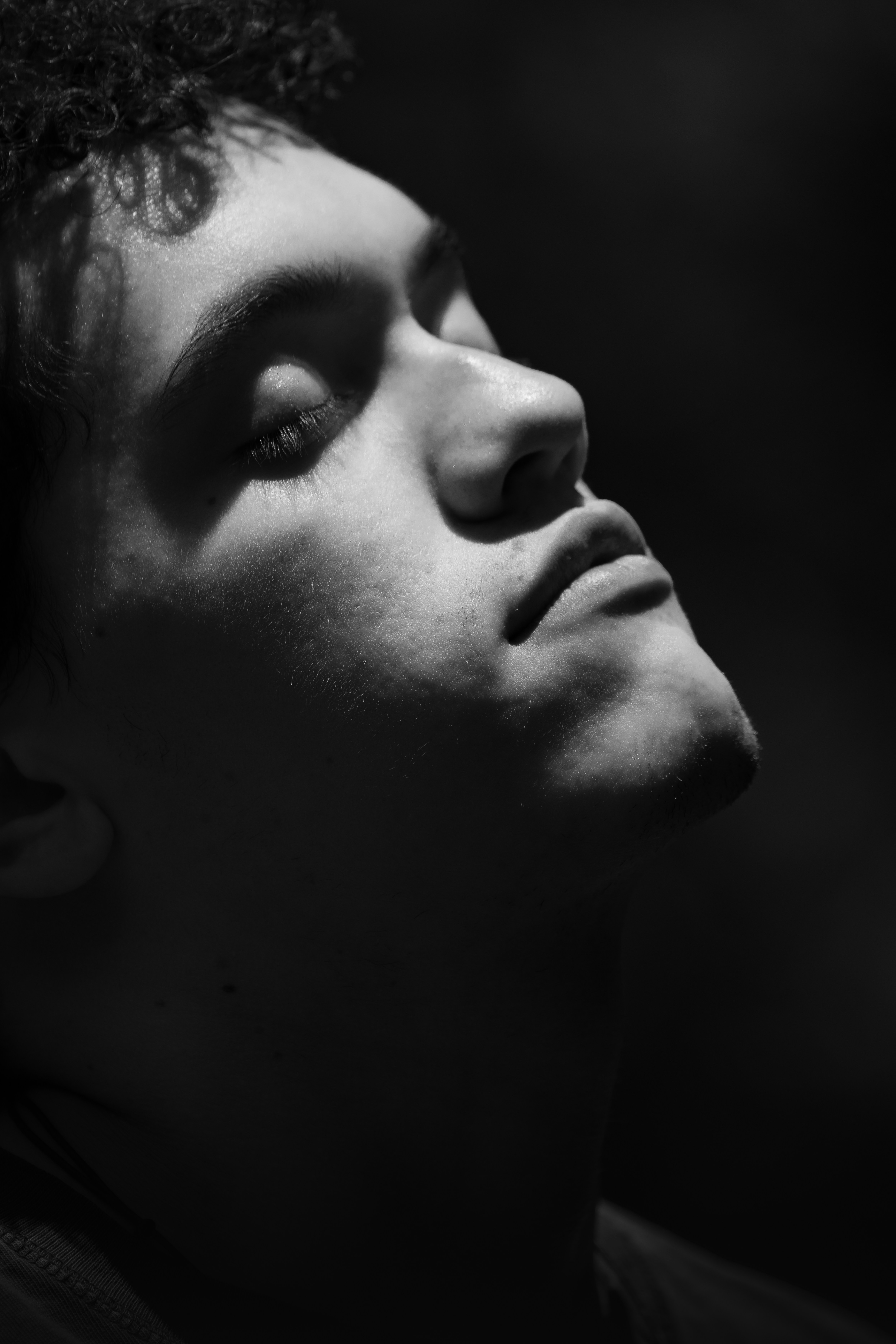 Man with closed eyes, head tilted back in dramatic light