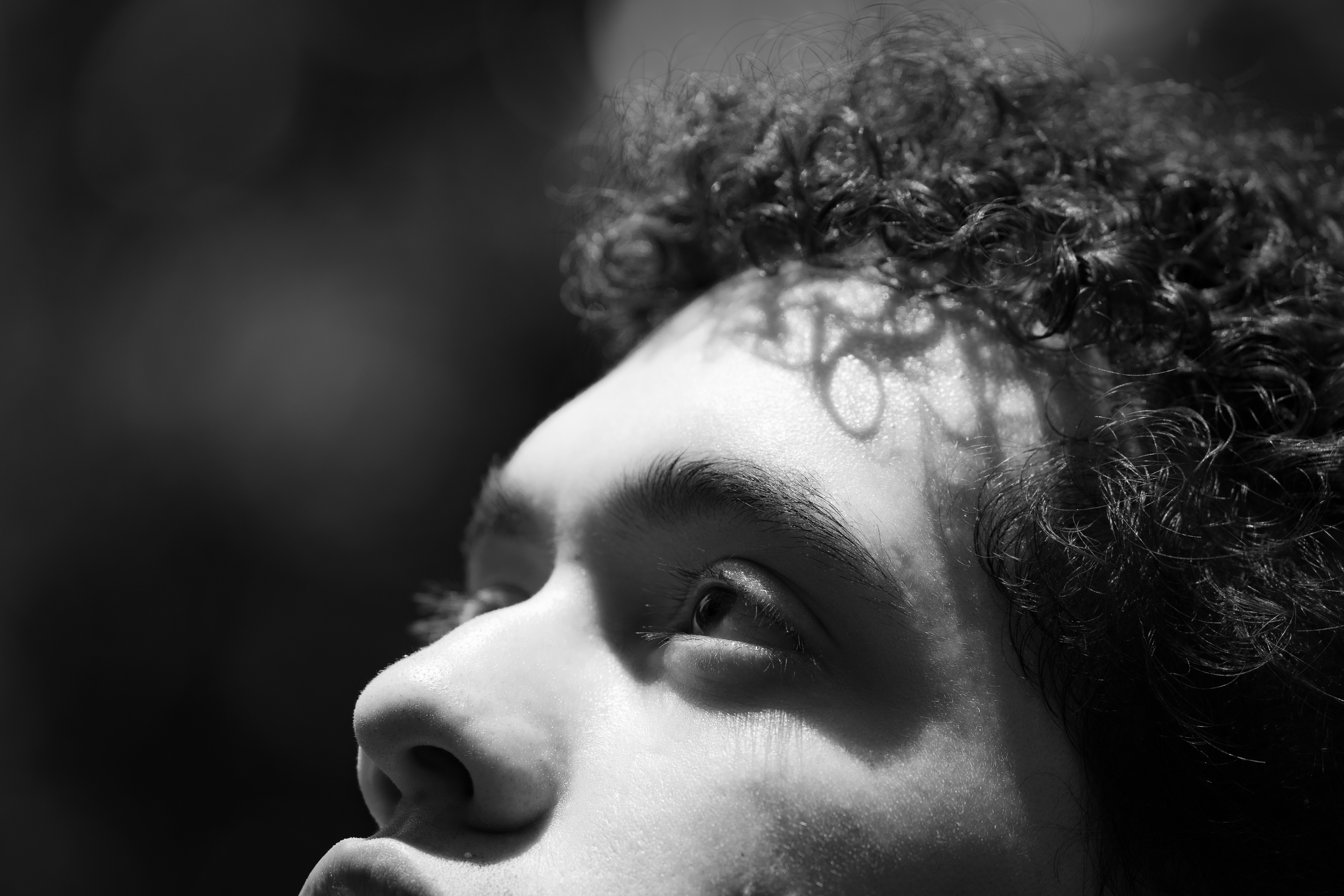 Curly-haired person looking upwards in black and white