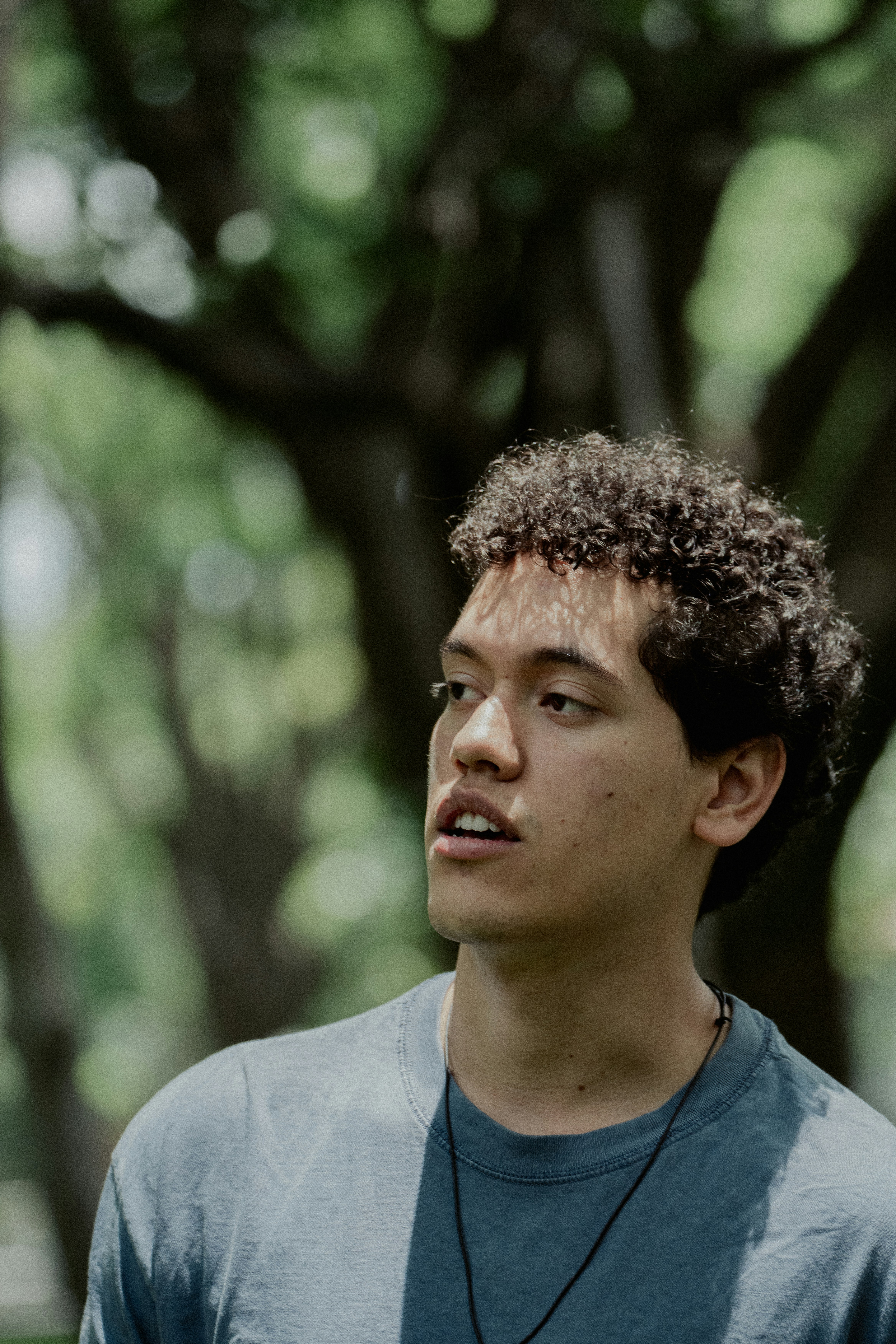 Young man with curly hair looking up outdoors